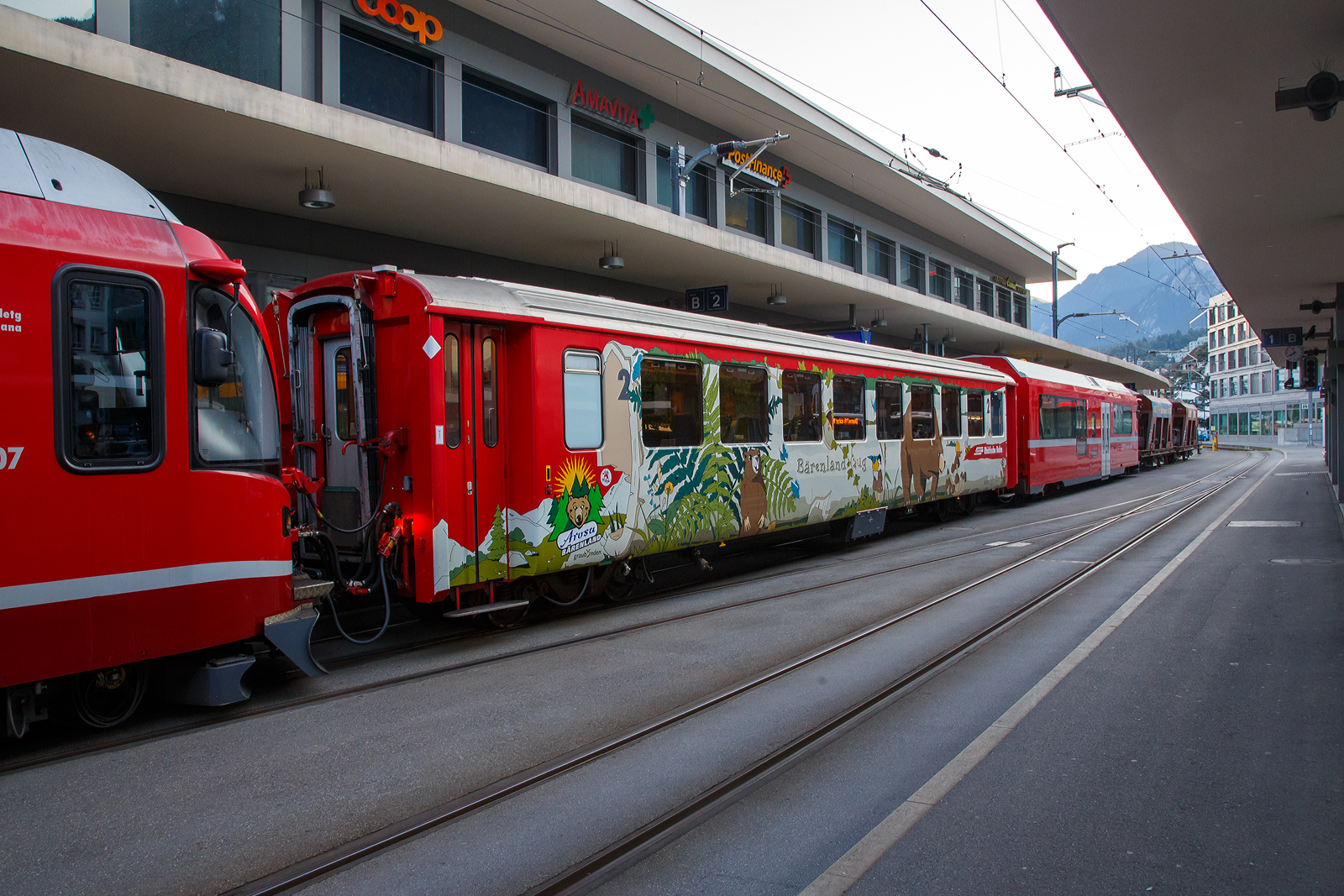 Der 4-achsige RhB Einheitswagen I (EW I) - B 2317  Bärenland Arosa , ein 2. Klasse Personenwagen am 07 September 2021in Chur am Bahnhofsvorplatz. Dahinter der Steuerwagen RhB Bt 52802, sowie zwei vierachsige Drehgestell-Schotterwagen (Schwerkraftentladewagen) RhB Fac 8712 und RhB Fac 8704.

Im August 2018 wurde bei Arosa das Bärenland eröffnet. Für diesen Anlass hat die RhB die Einheitswagen EW I B 2315 -2319 zu Bärenlandwagen innen und außen umgestaltet. Mit der Bahn anreisende Besucher können sich bereits während der Bahnfahrt zum Beispiel mit Büchern einstimmen.

Mit mehr als 100 Fahrzeugen bilden die als Einheitswagen I bezeichneten Personenwagen bis heute die größte Serie im Rollmaterialbestand der RhB. Das Fahrzeugkonzept wurde Anfang der sechziger Jahre in enger Zusammenarbeit zwischen Industrie und RhB entwickelt. Als Neuheit galten damals die Einstiegsbereiche mit WC und Stauraum für sperriges Gepäck an den Wagenübergängen. Folglich weicht das Konzept deutlich von den Mitteleinstiegswagen aus den vierziger Jahren ab.

Die ersten von FFA und SIG gebauten Einheitswagen I wurden Ende 1963 in Betrieb genommen. In einem Zeitraum von etwa zehn Jahren wuchs der Bestand an EW I kontinuierlich. Neben den 18,42 m langen Wagen, die hauptsächlich auf dem Stammnetz eingesetzt werden, kamen auch Sonderbauformen mit Aluminiumwagenkasten hinzu. Zu diesen zählen die auf 14,19 m verkürzten Fahrzeuge für den Einsatz auf der Berninabahn.

TECHNISCHE DATEN (B 2315-2319):
Hersteller Wagenkasten: FFA
Hersteller Drehgestelle: SWP
Inbetriebsetzung: 1969
Betriebsnummern: B 2315-2319
Anzahl Fahrzeuge: 5
Spurweite: 1.000 mm
Länge über Kupplung: 18.420 mm
Breite: 2.650 mm
Achsabstand im Drehgestell: 1.800 mm
Drehzapfenabstand: 12.830 mm
Gewicht: 13.000 kg
Sitzplätze: 62
zul. Höchstgeschwindigkeit: 90 km/h
Lauffähig: Chur-Arosa, StN (Stammnetz) / MGB (Matterhorn Gotthard Bahn)
Auf der BB (Berniabahn) wäre es möglich, aber nur bis Alp Grüm. Denn dahinter werden die Gleisradien zu eng. Für die BB wurden verkürzte Einheitswagen beschafft.