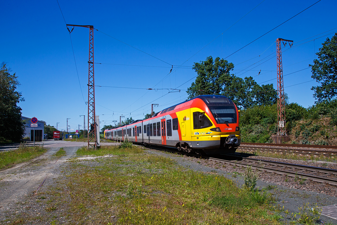 Der 5-teilige Stadler Flirt 429 046 / 429 546 der HLB Bahn (Hessischen Landesbahn) rauscht, als RE99 Siegen - Gießen - Frankfurt Hbf (Umlauf HLB 24511), am 10.08.2023 durch Rudersdorf in Richtung Dillenburg. 