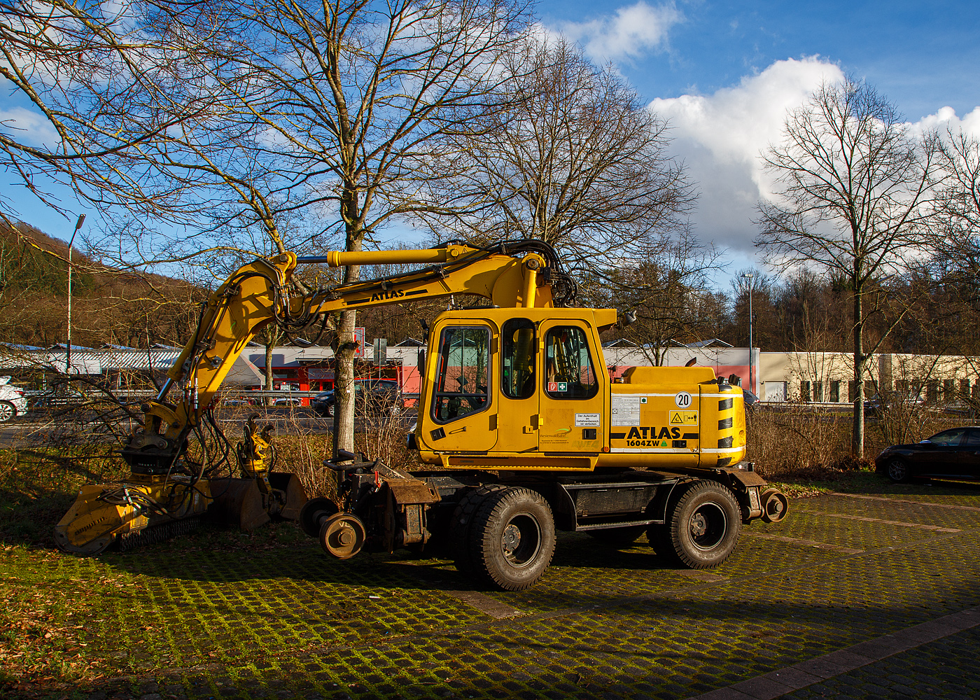 Der ATLAS-TEREX Zweiwegebagger 1604 ZW-WB mit Abstützpratzen, Kleinwagen Nr. D-WEBA 98 80 9901 683-9, der Westerwaldbahn des Kreises Altenkirchen GmbH ist am 07.02.2022, mit einem angebauten SEPPI Baggermulcher BMS 150 der HeringBau, in Betzdorf-Alsdorf auf einem Parkplatz neben Bahnstrecke Betzdorf–Daaden (Daadetalbahn) angestellt.

Der Bagger wurde 2005 ATLAS-TEREX GmbH in Delmenhorst unter der Fabriknummer 168Z301630 gebaut.

TECHNISCHE DATEN des Baggers:
Spurweite: 1.435 mm
Achsabstand: 5.475 mm (Schiene) / 2.550 mm (Straße)
Eigengewicht: 22,2 t
Zul. Gesamtgewicht: 23.000 kg
Motorbauart: wassergekühlter 4-Takt 4-Zylinder Diesel-Reihenmotoren mit Turboaufladung und Ladeluftkühlung
Motortyp: Deutz BF 4M 2012 C
Motorhubraum: 4,04 Liter (101mm / 126 mm Bohrung/Hub)
Motorleistung: 93 kW (127 PS) bei 2.500 U/min
Höchstgeschwindigkeit (Hg): 20 km/h (in Kreuzungen und Weichen 10 km/h)
Bremse: Dir.-Dbr. und Eisenbahnwagenbremsanlage
Zul. Anhängelast: 120 t
Zur Mitfahrt zugel. Personenzahl: 1 (und Fahrer)
Antrieb auf Schiene: Über Reibantrieb der Straßenreifen

Der angebaute Mulcher:
Der SEPPI BMS 150 ist ein leistungsvoller Forstmulcher. Dieser SEPPI Baggermulcher BMS mulcht (zerkleinert Holz) Stubben und Stämme bis zu 30 cm Durchmesser. Die Arbeitsbreite bei diesem BMS 150 beträgt 150 cm, das Gewicht beträgt 1.400 kg. Hersteller ist die SEPPI M. AG in Kaltern (Südtirol) – Italien.