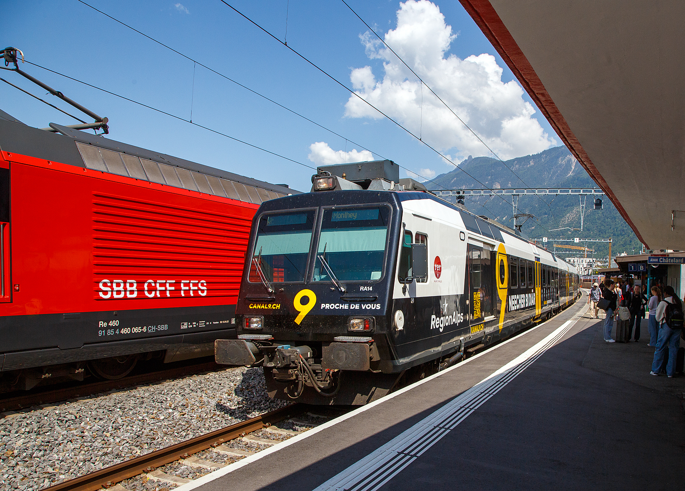 Der dreiteilige NPZ Domino RA14 der RegionAlps, mit der Vollwerbung für den Walliser Fernseh-Sender Kanal 9, verlässt am 26.Mai 2023, als Regionalzug nach Monthey den Bahnhof Martigny.

Der NPZ Domino besteht aus den Triebwagen RBDe 560 DO RA 94 85 7 560 414-5, dem 2.Klasse Wagen B NPZ DO RA 50 85 29-43 414-6 und dem 1./2. Klasse Steuerwagen ABt NPZ DO RA 50 85 39-43 954-9 CH-RA (ex SBB RBDe 560 276, ex SBB B 29-43 181 und ex SBB ABt 39-43 869).

Die Regionalps (RA) ist ein Eisenbahnverkehrsunternehmen im Kanton Wallis, mit Sitz in Martigny hat. Eigentümer derim Jahr 2003 gegründete Gesellschaft  sind die Schweizerischen Bundesbahnen (SBB) mit 70 %, die Transports de Martigny et Régions (TMR) mit 18 % und der Kanton Wallis mit 12 %. Die RA betreibt den Regionalverkehr vor allem im Rhonetal zwischen dem Ostufer des Genfersees und Brig. Inzwischen gehören Regionalps 16 dreiteilige NPZ Domino (Trieb-, Zwischen- und Steuerwagen ex SBB) und 4 RABe 525 NINA (ex TMR).
