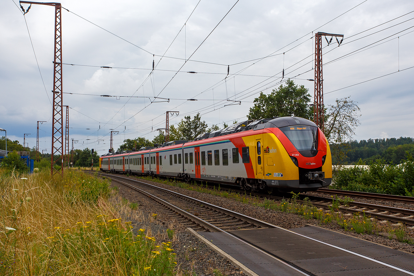 Der fast fabrikneue ET 263 (94 80 1440 263-0 / 1441 263-9 / 1841 263-5  / 1441 763-8 und 1440 763-9 D-HEB), ein fünfteiliger Niederflur-Elektrotriebwagen vom Typ Alstom CORADIA Continental 2 (XCC MHX) der HLB (Hessische Landesbahn GmbH), fährt am 01 August 2024, als RE 99 „Main-Sieg-Express“ (Gießen – Siegen) Umlauf HLB24562, vom Bahnhof Wilnsdorf-Rudersdorf (Kreis Siegen) weiter in Richtung Siegen. 

Der Elektrotriebzug wurden 2023 von der Alstom Transport Deutschland GmbH (vormals LHB) in Salzgitter-Watenstedt unter der Fabriknummer D041545-010 gebaut und an die HLB geliefert. Die Coradia Continental benötigten wegen einer neuen Steuerungssoftware eine neue Zulassung, nach Problemen mit dieser, hatte ALSTOM erst Ende April 2024 die Zulassung für die neuen Coradia Continental für die Hessische Landesbahn (HLB) erhalten und so erfolgte die Abnahme erst zum 30. April 2024.
