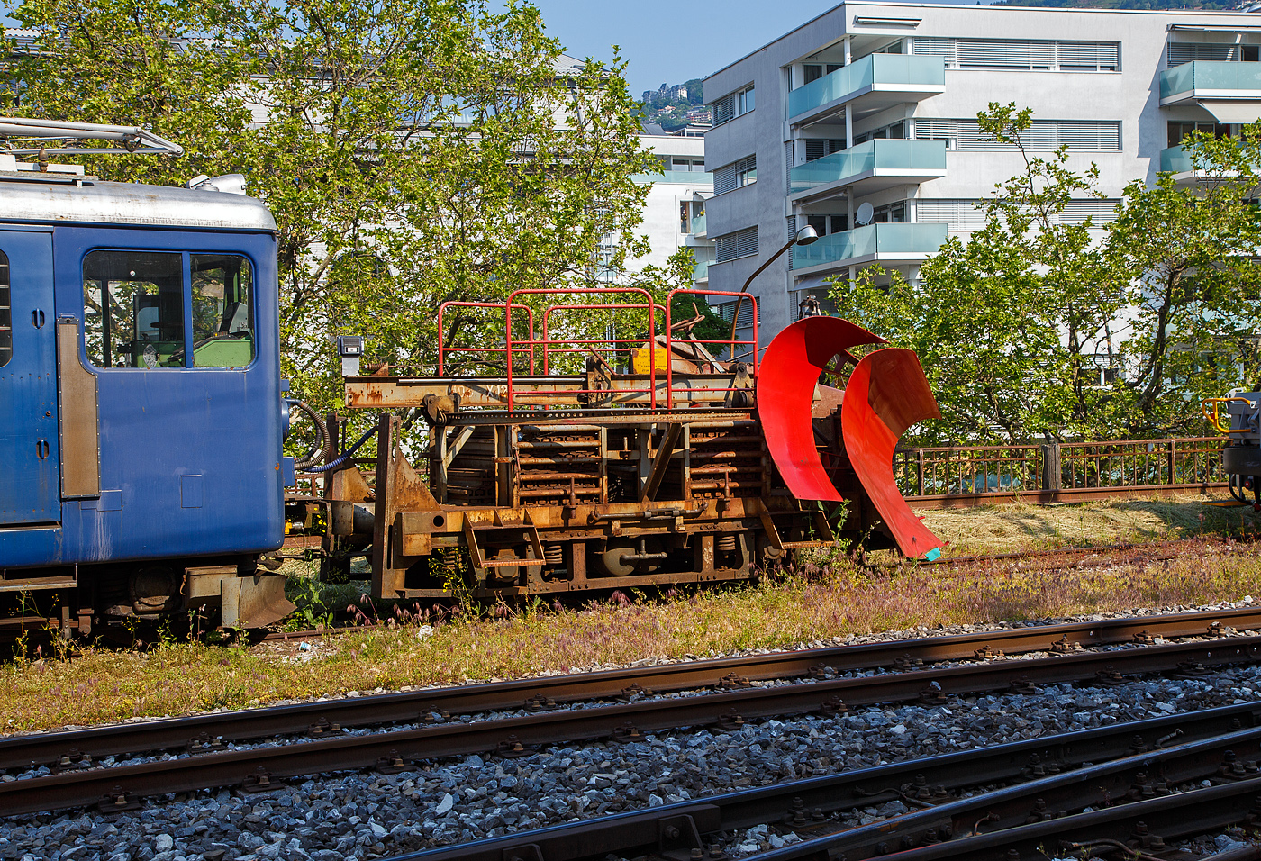 Der MOB Schneepflug X 12 vor dem Triebwagen BDe 4/4 3006 wartet am 28. Mai 2023 in Vevey noch auf Schnee.

Der Schneepflug wurde 1964 in den Werkst�tten der MOB auf ein altes SWS Drehgestell (vom B4 48) aufgebaut. 

Der doppelseitige Pflugkeil l�sst sich hydraulisch heben. Beidseitig ausklappbare Zusatzfl�gel. Der Pflug wird w�hrend der Fahrt nicht bedient, er kann aber gehoben und gesenkt werden. Um auf das hohe Gewicht von 12 t (6t Achsdruck)  zu kommen, sind liegen geschichtet in zwei Boxen etliche Schienenst�cke (Ballast 6,2 t). Im Jahr 2014 beikam der Pflug neue elektrische Anschl�sse, Hydraulikleitung und Hydraulikzylinder.

TECHNISCHE DATEN:
Hersteller/ Erbauer: MOB
Spurweite: 1.000 mm
Anzahl der Achsen: 2 
L�nge �ber Puffer: 4.520 mm (bzw. 5.610 mm �ber Pflugkeil)
Breite: 2.800 mm
Achsabstand: 2.300 mm
Laufraddurchmesser: 750 mm (neu)
Eigengewicht: 12t
V max: 50 km/h
Max Schneer�um H�he / Breite: 1.150 mm / 3.400 mm