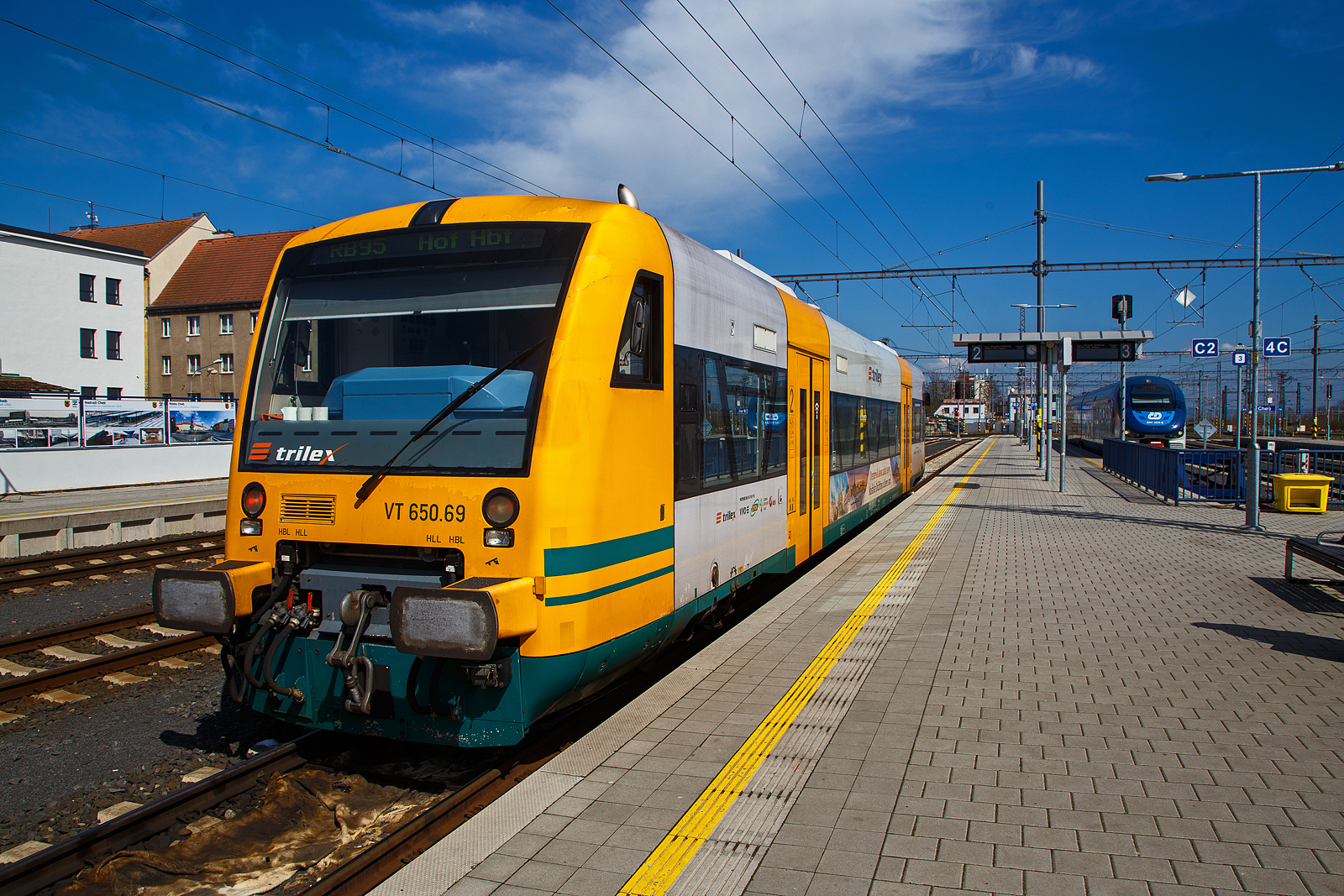 Der trilex VT 650.69 (95 80 0650 069-7 D-DLB), ein STADLER Regio-Shuttle RS1 der „oberpfalzbahn“ eine Marke der „Die Länderbahn GmbH (DLB)“, steht am 21.04.2023 im tschechischen Bahnhof Cheb (Eger), als RB 95 (ex OPB 2) Marktredwitz – Schirnding – Cheb – Hof Hbf, zur Weiterfahrt nach Hof bereit. Ich habe aber noch etwas Zeit für Fotos.

Der STADLER Regio-Shuttle RS1 wurde 2004 von der  Stadler Pankow GmbH in Berlin unter der Fabriknummer 37292 gebaut und als VT 650.69 an die PEG - Prignitzer Eisenbahn GmbH (ein Tochterunternehmen der NETINERA Deutschland GmbH) geliefert. Im Jahr 2013 kaufte die Oberpfalzbahn 2 gebrauchte RS1 von der Prignitzer Eisenbahn hinzu, einer davon ist dieser. So hat die Oberpfalzbahn nun 13 STADLER RS1 im Einsatz. Im Jahr 2014 wurden alle 13 Fahrzeuge dann modernisiert.

Die RS1 sind ursprünglich ein Produkt des Herstellers Adtranz, mit der Übernahme von Adtranz von Bombardier Transportation musste diese den Standort Berlin aus kartellrechtlichen Gründen verkaufen, der somit an die Stadler Rail AG ging. So hat dann Stadler die Produktion der RS1 übernommen.

Die 13 STADLER Regio-Shuttle RS1 (Baujahr 2000/03) der „oberpfalzbahn“ wurden 2013/2014 modernisiert (komplett entkernt und umgebaut). Für die kleinen Fahrgäste ist eine Kinderspielecke entstanden. Verbessert wurde auch die Fahrgastinformation im Fahrzeug. Neue Monitore wurden im Bereich des Aus- und Einstiegs eingebaut und informieren über den aktuellen Verlauf der Fahrt und die weiteren Anschlüsse. Zwei Mehrzweckbereiche pro Fahrzeug bieten ausreichend Platz für bis zu sechs Fahrräder, Kinderwagen und Gepäck. Der stufenlose Einstieg ermöglicht auch mobilitätseingeschränkten Personen einen bequemen Zugang. Das Fahrzeug bietet Platz für ca. 155 Fahrgäste (72 Sitzplätze). 

Der Antrieb erfolgt durch 2 MAN 6-Zylinder-Viertakt-Dieselmotor mit Direkteinspritzung vom Typ D 2866 LUH 21 mit je 257 KW (350 PS) Leistung, der  hydromechanisch über 2 Voith-Diwabus Getriebe U 864 übertragenen wird. Die Motoren haben einen Hubraum von je 12 Liter. Die Höchstgeschwindigkeit beträgt 120 km/h in Deutschland,  in Tschechien sind sie nur für 100 km/h zugelassen.

TECHBISCHE DATEN:
Spurweite: 1.435 mm
Achsfolge: B'B'
Länge über Puffer: 25.500 mm
Länge Wagenkasten: 24.260 mm
Drehzapfenabstand: 17.100 mm
Achsabstand im Drehgestell: 1.800 mm
Federung: 2 luftgefederte Triebdrehgestelle
Eigengewicht: 42 t
Leistung: 2 x 257 KW (350 PS)
Höchstgeschwindigkeit: 120 km/h (Tschechien 100 km/h)
Beschleunigung: 1,2 m/s²
Einstiegshöhe:  600 mm
Bremse: KBGM C-pn-P-A-H-Mg (D)
Fahrgastraum: klimatisiert
Plätze: 72 Sitzplätze, davon 18 als Klappsitze, 88 Stehplätze
Niederfluranteil: 65% bezogen auf die Länge des Fahrgastraumes
Türen: Vier 2-flügelige Automatik-Schwenkschiebetüren
Einstiegshilfe je Fahrzeugseite: Rollstuhl-Hublift an Tür L1 und R1
WC: behindertengerecht
Zulassungen für: Deutschland und Tschechien (D und CZ)