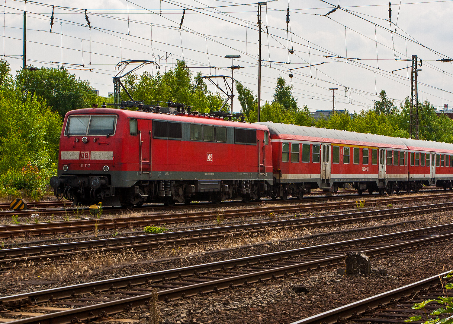 Die 111 112-9 (91 80 6111 112-9 D-DB) der DB Regio NRW ist mit fünf n-Wagen (ex Silberlinge), als Verstärkerzug für dem RE 9 - Rhein-Sieg-Express, am 14 Juli 2013 beim Hbf Siegen angestellt.

Die Lok wurde 1979 von Krauss-Maffei in München-Allach unter der Fabriknummer 19844 gebaut, die elektrische Ausrüstung von Siemens. Sie wurde als 111 112-9 an die Deutsche Bundesbahn geliefert. Im Jahr 2022 wurde sie an die TRI Train Rental GbR (Eckental-Eschenau) verkauft, wo sie nun in der schönen Farbgebung blau/schwarz unter der Betreiberbezeichnung E 11 112 (91 80 6111 112-9 D-TRAIN) fährt. Ich hoffe es sind noch einige Jahre.

Die Lok besitzt eine Konventionelle-Wendezug-Steuerung (36-poliges Kabel) und eine Zeitmultiplexe-Wendezug-Steuerung (UIC-Kabel).
