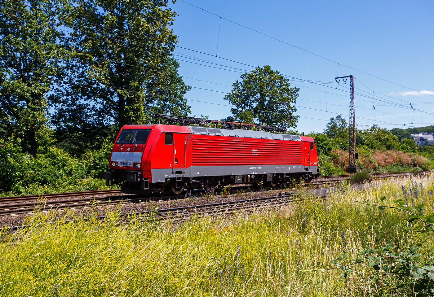 Die 189 024-3 (91 80 6189 024-3 D-DB) der DB Cargo AG rauscht am 28 Juni 2024, als Lz (Lokzug)/ auf Tfzf (Triebfahrzeugfahrt) durch Ruderdorf (Kreis Siegen) in Richtung Siegen.

Die SIEM;ENS ES 64 F4(EuroSprinter) wurde 2003 von SIEMENS in München-Allach unter der Fabriknummer 20699 gebaut und an die damalige Railion Deutschland AG (heute DB Cargo AG) in der Variante A ausgeliefert und war nur für Deutschland zugelassen. 2007 wurde sie in die Variante J umgebaut und besitzt nun die Zugbeeinflussungssysteme LZB/PZB, ETCS und ATB für
den Einsatz in Deutschland und den Niederlanden.

Die Stromabnehmerbestückung ist folgende: 
Pos. 1: D, NL (AC)
Pos. 2: NL (DC)
Pos. 3: NL (DC)
Pos. 4: D, NL (AC)

Die Elektrolokomotive ES64F4 ist eine Variante der EuroSprinter-Lokfamilie von Siemens Mobility (vormals Siemens Transportation Systems) mit Vier-Stromsystem-Ausstattung. In Deutschland ist sie vor allem als Baureihe 189 der Deutschen Bahn im Einsatz. Sie ist in allen vier in Europa üblichen Bahnstromsystemen einsetzbar. Für die verschiedenen Bahngesellschaften können die jeweils erforderlichen Zugsicherungssystem-Komponenten als „Paket“ installiert werden.

Die Lokomotiven haben eine elektrische Bremse und Scheibenbremsen. Diese sind wegen der vergleichsweise geringen zulässigen Höchstgeschwindigkeit von 140 km/h und aus Kostengründen als Radscheibenbremsen ausgeführt und nicht, wie bei Lokomotiven des Typs ES 64 U2, auf gesonderten Bremswellen angebracht. Die Konstruktion der Lok ist aber so ausgelegt, dass auch eine Version mit einer Höchstgeschwindigkeit von 230 km/h möglich ist.

Der ölgekühlte Transformator ist unterflur angeordnet, während er in der herkömmlichen Bauweise im Lok-Kasten untergebracht war. Dadurch wurde im Lokkasten ein durchgehender Mittelgang zwischen den Führerständen ermöglicht. Beiderseits des Mittelgangs befinden sich die Stromrichter-Gestelle. Je ein Stromrichtersatz versorgt die Fahrmotoren eines Drehgestelles. Er besteht aus Gleichrichtern, die die Sekundärspannung des Transformators zunächst in Gleichstrom umwandeln, sowie jeweils drei Motorstromrichtersätzen. Zur Glättung der Zwischenkreis-Gleichspannung sind Stützkondensatoren und Saugkreisdrosseln vorhanden. Die zeitlich versetzt taktenden Motorstromrichter formen den Gleichstrom in Drehstrom um und versorgen die Fahrmotoren einzeln. Dadurch können diese auch einzeln geregelt und der Reibwert Rad-Schiene optimal ausgenutzt werden.


Beim Betrieb in Gleichstrom-Netzen wird die Fahrleitungsspannung direkt in die Zwischenkreise eingespeist, wobei die Sekundärwicklungen des Trafos als Netzfilterdrossel genutzt werden.

Die Stromrichter ermöglichen zusammen mit der elektrischen Bremse auch eine Bremsstrom-Rückspeisung mit einer Bremsleistung von theoretisch 6,4 MW. Die Bremskraft ist aber aus Gründen der Entgleisungssicherheit auf 150 kN begrenzt.

TECHNISCHE DATEN:
Spurweite: 1.435 mm (Normalspur)
Achsformel: Bo’Bo’
Länge über Puffer: 19.580 mm
Drehzapfenabstand: 9.900 mm
Achsstand im Drehgestell: 2.900 mm
Treibraddurchmesser: 1.250 mm (neu)
Dienstgewicht: 87 t
Stundenleitung: 6.400 kW bei 15 kV / 25 kV AC; 6.000 kW bei 3 kV DC und 3.000 kW bis 4.200 kW bei 1,5 kV DC
Anfahrzugkraft: 300 kN
Maximale Dauerzugkraft bis 84 km/h; 270 kN
Höchstgeschwindigkeit: 140 km/h
E-Bremskraft max.: 150 kN
Stromsysteme: 15 kV, 16,7 Hz AC; 25 kV, 50 Hz AC; 1,5 kV und 3 kV DC 
Kleinster befahrbarer Gleisbogen: R = 80 m