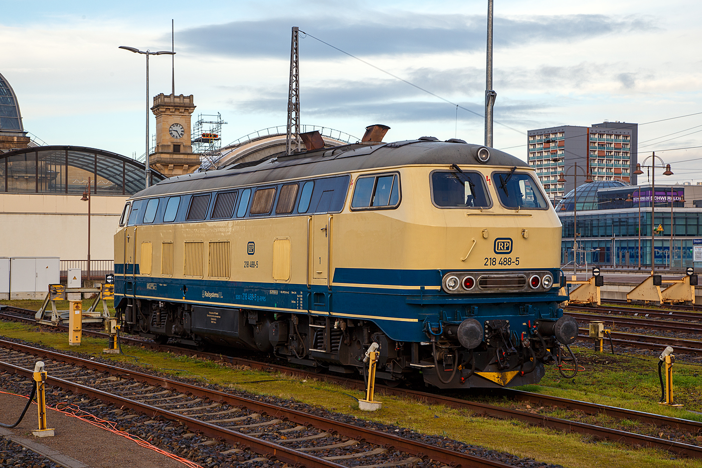 Die 218 488-5 (92 80 1218 488-5 D-RPRS) der Railsystems RP GmbH (Gotha) ist am 08.12.2022 auf einem der Abstellgleisen im Hauptbahnhof Dresden (Ost) angestellt.

Die V 164 wurde 1978 von der Krauss-Maffei AG in München-Allach unter der Fabriknummer 19803 gebaut und an die DB geliefert, bis 2018 war sie in verkehrsrot im Bestand der DB Regio Südost (Leipzig). Nun ist sie bei der Railsystems RP GmbH. Die Lok hat die Zulassungen für D, A, B, CH, F, DK und CS (Serbien und Montenegro).

Die Railsystems RP GmbH halt als Einsatzbestand 11 Fahrzeuge dieser Baureihe. Die 218 488 hat eine 36-polige Doppeltraktions- und Wendezugsteuerung, sowie eine Zugsammelschiene (AEG). 

TECHNISCHE DATEN:
Spurweite: 1.435 mm (Normalspur)
Achsformel:  B'B'
Spurweite:  1.435 mm
Länge: 16.400 mm
Drehzapfenabstand:  8.600 mm
Achsabstand im Drehgestell: 2.800 mm
Gewicht:  79 Tonnen
Achslast: 20 t
Höchstgeschwindigkeit:  140 km/h
Motor: Wassergekühlter V 12 Zylinder Viertakt MTU - Dieselmotor vom Typ 12 V 952 TB 10 mit Direkteinspritzung und Abgasturboaufladung mit Ladeluftkühlung
Motorleistung: 1.839 kW (2.500 PS) bei 1.500 U/min
Anfahrzugkraft: 235kN / Dauerzugkraft: 175kN
Getriebe: MTU-Getriebe K 252 SUBB (mit 2 hydraulische Drehmomentwandler)
Leistungsübertragung: hydraulisch
Tankinhalt:  3.150 l
Bremse: KE-GPP-R-H mZ
Besonderheiten: doppeltraktionsfähig / wendezugfähig, elektrische Zugsammelschiene
