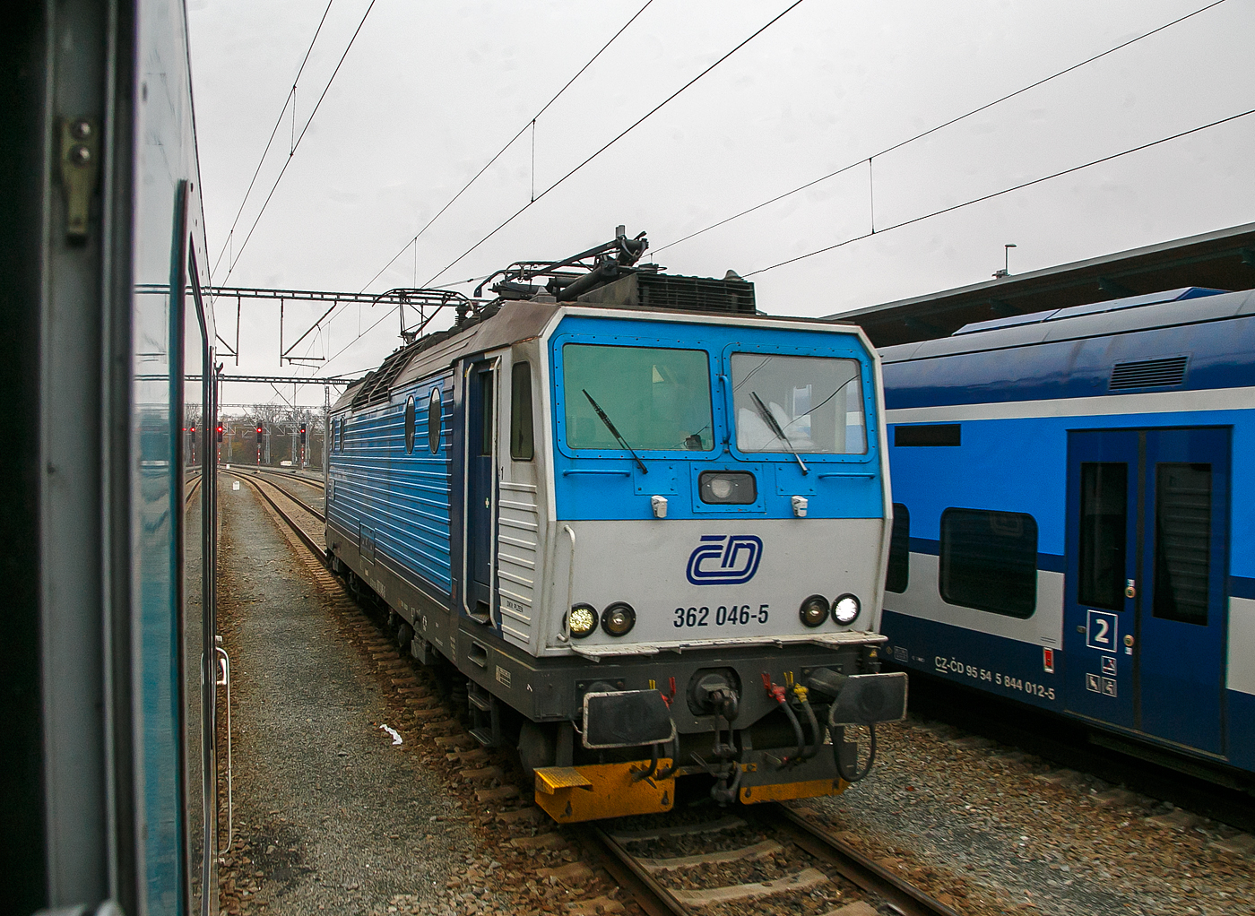 Die ČD 362 046-5 (CZ-ČD 91 54 7 362 046-5) der České dráhy (Tschechische Bahnen) rangiert am 22.11.2022 im Hauptbahnhof Pilsen (Plzeň hlavní nádraží), Zuvor hatte sie einen EX-Zug nach München (alex RE 25) von Prag nach Pilsen gezogen, ab hier dann die alexa 223 065 den Zug übernommen und zieht diesen bis Regensburg, wo wiederum eine 183er den Zug übernimmt.

Die Baureihe ČD 362 entstand aus Umbauten der 1984 bis 1990 von Škoda in Plzeň (Typ Škoda 69E) gebauten ČSD Baureihe ES 499.1 (ab 1988 BR 363). Die Loks sind elektrische Zweisystemlokomotiven für den universellen Einsatz. Sie sind sowohl im 3-kV-Gleichstromsystem im Norden und Osten wie auch im 25-kV-Wechselstromsystem im Westen und Süden der ehemaligen Tschechoslowakei einsetzbar.

Bereits 1990 wurde als Baureihe 362 erstmals eine 140 km/h schnelle Weiterentwicklung der ES 499.1/363 vorgestellt, wegen finanzieller Schwierigkeiten wurde auf eine Bestellung verzichtet. So wurden in den Jahren 1993/1994 und 2000/2001 Loks der BR 363 durch Anhebung der Höchstgeschwindigkeit von 120 auf 140 km/h zur BR 362 umgebaut. Dafür wurden die Drehgestelle mit solchen der Baureihe 162 ausgetauscht.

TECHNISCHE DATEN:
Spurweite: 1.435 mm (Normalspur)
Achsformel: Bo’Bo’
Länge über Puffer:  16.800 mm
Höhe:  4.625 mm
Breite:  2.940 mm
Drehzapfenabstand:  8.300 mm
Dienstgewicht:  87 t
Höchstgeschwindigkeit:  140 km/h
Dauerleistung:  3.060 kW (25 kV~) / 3.480 kW (3 kV=)
Anfahrzugkraft:  258 kN
Stromsystem:  3 kV DC und 25 kV 50Hz AC
Anzahl der Fahrmotoren:  4 (Typ Al 4542 FiR)
Antrieb:  Škoda-Hohlwellenantrieb
Zugheizung:  3000 V
Steuerung:  Thyristor-Pulsumrichter
Kupplungstyp:  Schraubenkupplung