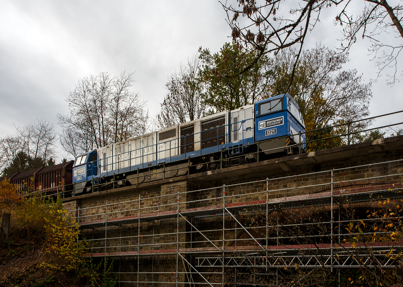 Die an die KSW vermietete 272 409-4 / D21 (92 80 1272 409-4 D-BE) der Bentheimer Eisenbahn, ex Rurtalbahn V 204 (92 80 1272 409-4 D-RTBC), eine Vossloh G 2000 BB (mit symmetrischem Führerhaus), fährt am 31 Oktober 2025 mit ihrem Coilzug zwischen Sassenroth und Herdorf nun über die erste Hellerbrücke. 