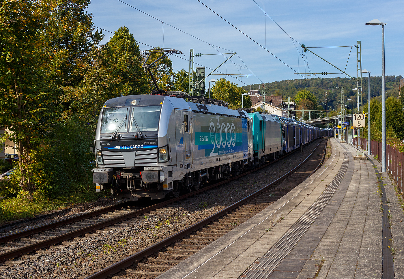 Die an die RTB Cargo vermietete SIEMENS Vectron MS 6193 094-0 (91 80 6193 094-0  D-Rpool) der Railpool GmbH in München fährt am Sonntag den 22 September 2024, mit der kalten auch an die RTB Cargo vermietete Bombardier TRAXX F140 AC2 – 185 612-9 (91 80 6 185 612-9 D-ATLU) und einem mit langen Hödlmayer Autotransportzug (Touax-Wagen der Gattung Laaers), durch den Bahnhof Kirchen/Sieg in Richtung Köln. Die SIEMENS Vectron trägt die Werbung: SIEMENS 23.000 Lokomotiven aus München. 

Die Multisystemlokomotive Siemens Vectron MS wurde 2022 von SIEMENS Mobilitiy in München-Allach unter der Fabriknummer 23000 gebaut. Sie wurde in der Variante MS A17 ausgeführt und hat so die Zulassungen für Deutschland, Österreich, Polen, Tschechien, die Slowakei, Ungarn, Rumänien, Slowenien, Kroatien und Bulgarien (D-A-PL-CZ-SK-H-RO-SL-HR-BG).  Für Serbien (SRB) ist auch eine Zulassung vorgesehen, aber ist z.Z. noch durchgestrichen. 

So besitzt die Variante MS A17 folgende Zugsicherungssysteme: ETCS BaseLine 3, sowie für Deutschland (PZB90 / LZB80 (CIR-ELKE I)), für Österreich (ETCS Level 1 mit Euroloop, ETCS Level 2, PZB90 / LZB80), für Polen (SHP, für Tschechien und Slowakei (LS (Mirel)), für Ungarn (ETCS Level 1, EVM (Mirel)), sowie für Rumänien, Slowenien und Kroatien (PZB90).

Die Bombardier TRAXX F140 AC2 wurde 2008 von Bombardier in Kassel unter der Fabriknummer 34263 gebaut. Sie hat die Zulassung (140 km/h) für Deutschland, Österreich und Ungarn.
