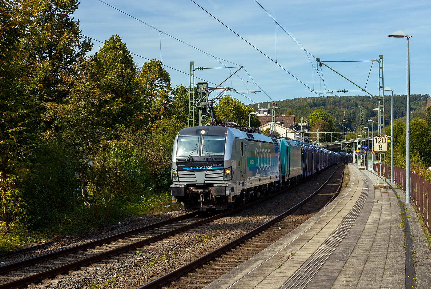 Die an die RTB Cargo vermietete SIEMENS Vectron MS 6193 094-0 (91 80 6193 094-0  D-Rpool) der Railpool GmbH in München fährt am Sonntag den 22 September 2024, mit der kalten auch an die RTB Cargo vermietete Bombardier TRAXX F140 AC2 – 185 612-9 (91 80 6 185 612-9 D-ATLU) und einem mit langen Hödlmayer Autotransportzug (Touax-Wagen der Gattung Laaers), durch den Bahnhof Kirchen/Sieg in Richtung Köln. Die SIEMENS Vectron trägt die Werbung: SIEMENS 23.000 Lokomotiven aus München. 

Die Multisystemlokomotive Siemens Vectron MS wurde 2022 von SIEMENS Mobilitiy in München-Allach unter der Fabriknummer 23000 gebaut. Sie wurde in der Variante MS A17 ausgeführt und hat so die Zulassungen für Deutschland, Österreich, Polen, Tschechien, die Slowakei, Ungarn, Rumänien, Slowenien, Kroatien und Bulgarien (D-A-PL-CZ-SK-H-RO-SL-HR-BG).  Für Serbien (SRB) ist auch eine Zulassung vorgesehen, aber ist z.Z. noch durchgestrichen. 

So besitzt die Variante MS A17 folgende Zugsicherungssysteme: ETCS BaseLine 3, sowie für Deutschland (PZB90 / LZB80 (CIR-ELKE I)), für Österreich (ETCS Level 1 mit Euroloop, ETCS Level 2, PZB90 / LZB80), für Polen (SHP, für Tschechien und Slowakei (LS (Mirel)), für Ungarn (ETCS Level 1, EVM (Mirel)), sowie für Rumänien, Slowenien und Kroatien (PZB90).

Die Bombardier TRAXX F140 AC2 wurde 2008 von Bombardier in Kassel unter der Fabriknummer 34263 gebaut. Sie hat die Zulassung (140 km/h) für Deutschland, Österreich und Ungarn.
