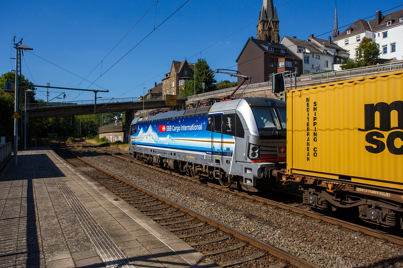Die an die SBB Cargo International AG vermietete Siemens Vectron MS - 193 110  Zugersee  (91 80 6193 110-4 D-Rpool) der Railpool GmbH (München) fährt am 18 August 2025 mit einem Containerzug durch den Bahnhof Kirchen/Sieg in Richtung Siegen. 

Die SIEMENS Vectron MS (X4E) wurde 2023 von Siemens Mobility in München-Allach unter der Fabriknummer 23293 gebaut. Die mit 6.400 kW konzipierte Mehrsystemlok ist in der Variante A22 ausgeführt und hat so die und hat so die Zulassungen und entspr. Länderpakete für Deutschland, Österreich, Schweiz, Italien und die Niederlande (D / A / CH / I / NL), wobei z.Z. CH und I noch durchgestrichen sind. Sie ist die 300th Lokomotive der Railpool. 