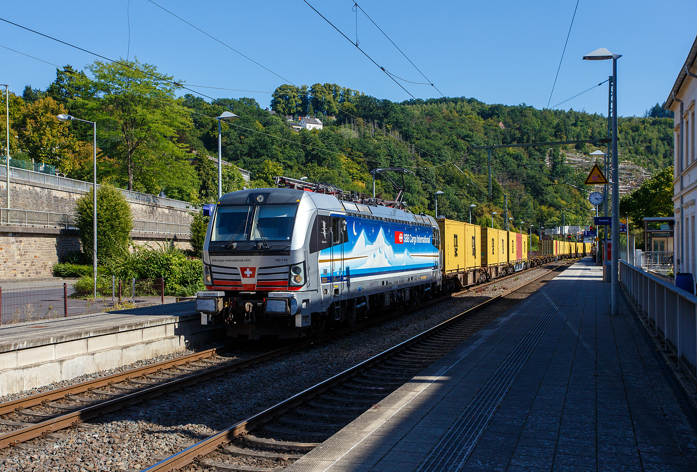 Die an die SBB Cargo International AG vermietete Siemens Vectron MS - 193 110  Zugersee  (91 80 6193 110-4 D-Rpool) der Railpool GmbH (München) fährt am 18 August 2025 mit einem Containerzug durch den Bahnhof Kirchen/Sieg in Richtung Siegen. 

Die SIEMENS Vectron MS (X4E) wurde 2023 von Siemens Mobility in München-Allach unter der Fabriknummer 23293 gebaut. Die mit 6.400 kW konzipierte Mehrsystemlok ist in der Variante A22 ausgeführt und hat so die und hat so die Zulassungen und entspr. Länderpakete für Deutschland, Österreich, Schweiz, Italien und die Niederlande (D / A / CH / I / NL), wobei z.Z. CH und I noch durchgestrichen sind. Sie ist die 300th Lokomotive der Railpool. 