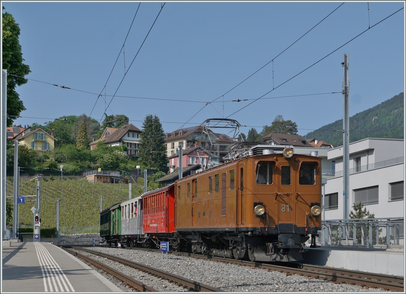 Die Bernina Bahn RhB Ge 4/4 81 der Blonay-Chamby Bahn ist mit ihrem recht gut besetzten Riviera Belle Epoque Zug von Chaulin auf dem Weg von Chaulin nach Vevey und wartet in St-L�gier Gare auf den Gegenzug.

28. Mai 2023