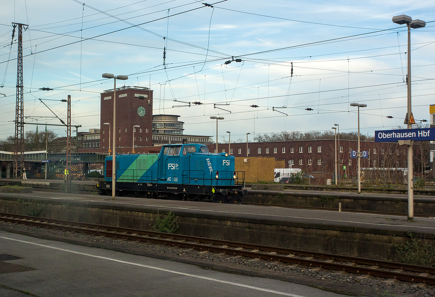 Die Deutz DG 1200 BBM - 423 001-7 „Ender“ (98 80 3423 001-7 D-FSI) der FSI Logistik GmbH (Teil der AY Holding GmbH) kommt unserem ICE (aus diesem fotografiert) am 14 M�rz 2014 entgegen im Hauptbahnhof Oberhausen entgegen. 

Ein Jahr nach der Einf�hrung der 1.000 PS-Lok DG 1000 BBM stand ein leistungsst�rkerer Motor zur Verf�gung, so dass jetzt mit der DG 1200 BBM nochmal 200 PS mehr an Traktionsleistung angeboten werden konnten. So wurde diese Lok als erste dieses Typs 1960 von Deutz unter der Fabrik-Nr. 57100 gebaut und an die OHE - Osthannoversche Eisenbahnen AG in Celle als OHE 120071 geliefert. Im April 1960 wurde sie auf der Deutschen Industriemesse Hannover pr�sentiert. Der damalige Kaufpreis betrug 495.000 DM. In den 1990er-Jahren erhielt die Lok in der Hauptwerkstatt OHE - Osthannoversche Eisenbahnen AG einen Umbau und die Remotorisierung mit dem heutigen Motor vom Typ MTU 12V396TC12. 

2007 bekam sie vom EBA die NVR-Nummer  98 80 3423 001-7 D-OHE, im August 2012 wechselte sie in Cargo Sparte (OHE Cargo GmbH) und bekam die UIC-Nummer 98 80 3423 001-7 D-OHEGO. Im Dezember 2016 ging sie an Talbot Services GmbH in Aachen als 98 80 3423 001-7 D-TAL und 2022 wurde sie an die FSI Logistik GmbH verkauft.

Die KHD DG 1200 BBM ist eine Vierachsige Diesellokomotive mit der Achsfolge B'B', von ihr wurden 18 Exemplare von 1960 bis 1966 gebaut. Die DG 1200 BBM war die leistungsst�rkste Lokomotive des Deutz-Typenprogramms 1959. Sie stellt eine verst�rkte Version der DG 1000 BBM dar. 

Jeweils vier Loks sind in die Niederlande und nach Italien verkauft worden. Eine Lok wurde verschrottet.

TECHNISCH DATEN:
Spurweite: 1.435 mm (Normalspur)
Achsformel: B'B'
L�nge �ber Puffer: 13.500 mm
Dienstgewicht: 80 t
H�chstgeschwindigkeit: 70 km/h
Urspr�nglich verbauter Motor: Deutz wassergek�hlter V-Zw�lfzylinder-Zweitakt-Dieselmotor mit Direkteinspritzung vom Typ KHD BT12M625. Der Motor hatte eine Zylinderbohrung von 200 mm und einen Kolbenhub von 250 mm. Damit hatte der Motor einen Hubraum von 94,2 l.

Heute verbauter Motor: Wassergek�hlter V-Zw�lfzylinder-Viertakt-Dieselmotor  mit Turboaufladung und Ladeluftk�hlung, sowie mit Direkteinspritzung , vom Typ MTU 12V 396 TC 12. Der Motor hat ein Zylinderbohrung von 165 mm und einen Kolbenhub von185 mm. Damit hat der Motor einen Hubraum von 47,5 l.
Installierte Leistung: 880 kW (1.200 PS)
Getriebe: Voith L306r

Die Typenbezeichnung   DG 1200 BBM   bedeutet:
D - Gro�diesellok
G - Kraft�bertragung �ber Gelenkwelle
1 2 0 0	- Motorleistung (rund 1200 PS)
B B - Achsfolge (Lok mit Drehgestell mit je zwei Achsen)
M - Mittelf�hrerhaus
