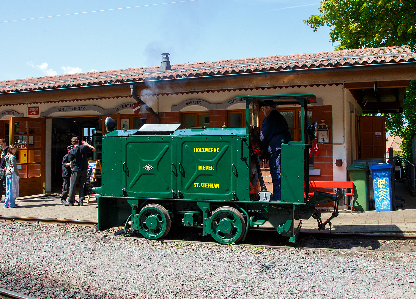 Die doch recht kleine ex MOB Schienentraktor Tm 2/2 Nr. 1, ex Holzwerk Rieder, der Museumsbahn Blonay-Chamby rangiert am 27.05.2023 im Museumsareal in Chaulin. 

Die kleine Diesellok, vom Typ O&K RL 2a wurde 1931 von Orenstein & Koppel im Werk Babelsberg unter der Fabriknummer 20200 gebaut und an die Grande Dixence SA für die Baustelle der ersten Dixence-Staumauer  geliefert, wo sie bis 1940 im Einsatz war. Im 1941 wurde sie dann von der Firma Mauerhofer & Zubner, für den Einsatz von Bauzügen beim Fahrleitungsumbau bei der MOB übernommen. 1950 wurde die kleine Lok an das Holzwerk Rieder in St. Stephan verkauft, diese Farbgebung trägt sie auch aktuell bei der BC. Die Lok trägt Fabrikschilder der MBA, wobei die Umbenennung der O&K in Maschinenbau und Bahnbedarf Aktiengesellschaft, vormals Orenstein & Koppel (MBA) erst im Februar 1940 erfolgte.

Die MOB (Montreux-Berner Oberland-Bahn / Montreux Oberland Bernois) kaufte die Lok dann 1979 wieder zurück und bezeichnete sie als Tm 2/2 1. Bei der MOB wurde sie für Rangierarbeiten, von Zementwagen auf Rollböcken in St. Stephan eingesetzt. Die Lok wurde 1995 von der MOB ausrangiert verbleib aber erst noch im Depot Montbovon. 2006 ging sie dann an die Museumsbahn Blonay-Chamby.

Die Lok hat einen 2-Zylinder-Orenstein & Koppel-Dieselmotor mit 22 PS (16 kW) Leistung, die Leistungsübertragung erfolgt über ein Zweigang-Konuskupplungs-Wendegetriebe mit stufenloser Geschwindigkeit Regulierung, über zwei Rollenketten auf die vordere Achse und von dieser über eine Rollenkette auf die hintere Achse. Das Zweigang-Konuskupplungsgetriebe ermöglicht zwei verschiedene Geschwindigkeitsstufen für beide Fahrtrichtungen. Dabei laufen immer beide Gänge im Eingriff, jeweils einer wird eingekuppelt. Eine einfache Wendeschaltung im Getriebe ermöglicht den Fahrtrichtungswechsel bei Stillstand der Lokomotive. Die einfache Bauart des Getriebes hat sich schon bei den Benzinloks bewährt und wurde bei fast allen O&K-Loks der unteren Leistungsklassen angewendet.

TECHNISCHE DATEN:
Spurweite: 1.000 mm (Meterspur)
Achsfolge: B
Länge über Puffer: 4.490 mm
Kastenlänge: 3.450 mm
Höhe: 2.270 mm
Breite: 1.240 mm
Achsabstand: 1.170 mm
Raddurchmesser : 550 mm
Eigengewicht: 7.000 kg
Leistung: 16 kW (22 PS)
Höchstgeschwindigkeit: 7 km/h
Achslager: Gleitlager

Die O&K Typenbezeichnung  RL  stand für  Rohöl  (= Diesel).

Anfang des 20. Jahrhunderts war es noch üblich bei und auf Großbaustellen Feld- oder Schmalspurbahnen zu bauen und zu betreiben. Heute durch Entwicklung von moderner und oft sehr schweren Baumaschinen und Muldenkipper eigentlich undenkbar.