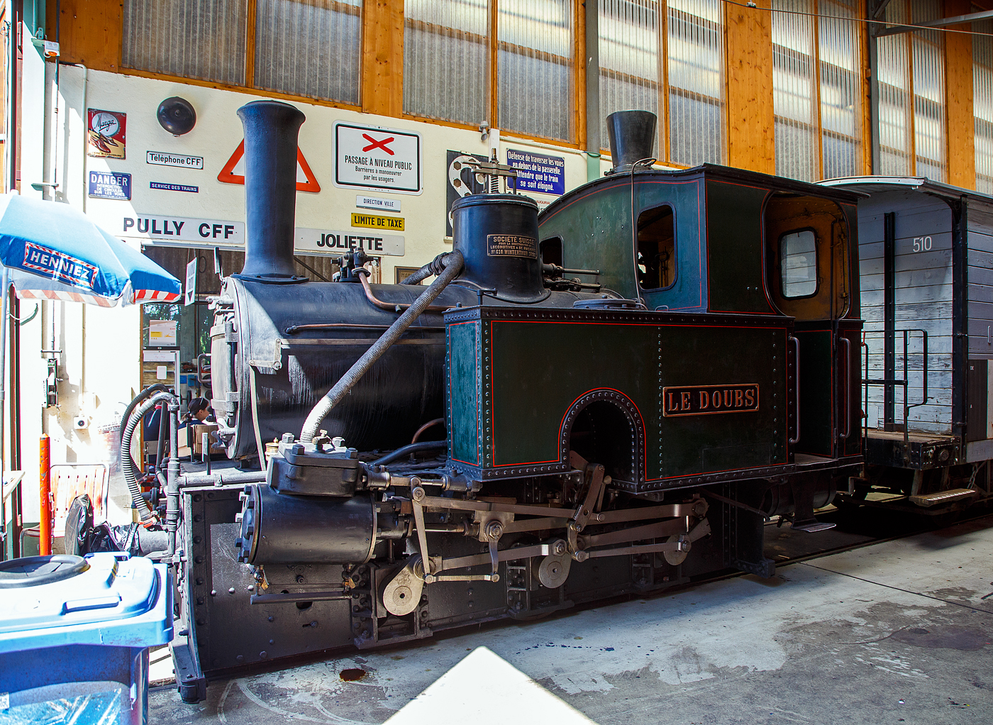 Die ehemalige Dampflokomotive RbB G 3/3 Nr. 1  Le Doubs  der Museumsbahn Blonay-Chamby, hier am 27.05.2023 in der Halle der (BC) in Chaulin.

Die Lok wurde 1890 von SLM (Schweizerische Lokomotiv- und Maschinenfabrik) unter der Fabriknummer 618 gebaut und an die kleine Bahngesellschaft Régional des Brenets geliefert. Am Fabrikschild steht auch der französische Name der SLM „Societe Suisse pour la construction de locomotives et de la Machines“

Das Ende des 19. Jahrhunderts war das goldene Zeitalter der dampfenden Lokalbahnen. So wurde am 1. September 1890 von der Chemin de fer Régional des Brenets (RdB) die meterspurige ca. 4 km lange Bahnstrecke von Le Locle (beginnt neben dem Normalspurigen der SBB) nach Les Brenets eingeweiht, um vor allem Touristen die in die kleine Gemeinde zu bringen. Les Brenets ist ein beliebtes Ausflugsziel dank seiner schönen Lage, dem Lac des Brenets und dem am Doubs unterhalb des Sees liegenden 27 m hohen Wasserfall Saut du Doubs.

Drei kleine Lokomotiven teilen sich den Betrieb, die 1  Le Doubs , 2  Père Frédéric  und 3  Les Brenets. Das weitere Rollmaterial bestand aus 8 Personenwagen und 2 Güterwagen.

Aufgrund der schlechten wirtschaftlichen Lage wurde auf Basis des Privatbahnhilfegesetzes von 1939 die Fusion mit der ebenfalls meterspurigen Ponts–Sagne–Chaux-de-Fonds-Bahn (PSC) in die Wege geleitet, obwohl keine Gleisverbindung zu dieser besteht. Umgesetzt wurde die Fusion 1947, woraus die Chemins de fer des Montagnes Neuchâteloises (CMN) entstand. Unter der CMN wurde die Bahnstrecke Le Locle–Les Brenets modernisiert und der elektrische Betrieb unter 1500 Volt Gleichstrom mit neuem Rollmaterial am 1. Juli 1950 aufgenommen. Seit 1999 wird die isolierte Bahnlinie von der Transports Publics Neuchâtelois (TransN) betrieben.

Nach der Elektrifizierung im Jahr 1950 wurden die Lokomotive 1 sowie die Wagen AB 2 und BD 21 an die SBB zur Aufnahme in die Sammlung des Luzerner Museums gespendet. Da Platz fehlte, wurde das Rollmaterial in Vallorbe abgestellt und 1973 an die Blonay-Chamby ausgeliehen. 1976 gingen die Lokomotive und Wagen in den Besitz der BC über.

Überraschenderweise wurde bei der Elektrifizierung der Strecke 1950 keine Dampflokomotive abgerissen, und alle drei Maschinen haben bis heute überlebt. Die G 3/3 2  Le Père Frédéric  steht als Denkmal überdacht in Les Brenets.

TECHNUISCHE DATEN:
Baujahr: 1890
Hersteller: SLM (Fabrik-Nr. 618)
Spurweite: 1.000 mm
Achsformel: C
Länge über Puffer: 5.210mm
Achsabstand: 1.800 mm (2 x 900mm)
Dienstgewicht: 16 t
Anzahl der Zylinder: 2
Zylindergröße: Ø 240 mm x 350 mm Kolbenhub
Treibraddurchmesser: 750 mm
Höchstgeschwindigkeit: 25 km/h
Kesselüberdruck: 12 bar
Kohlevorrat: 0,5 t
Wasservorrat: 1,8 m³