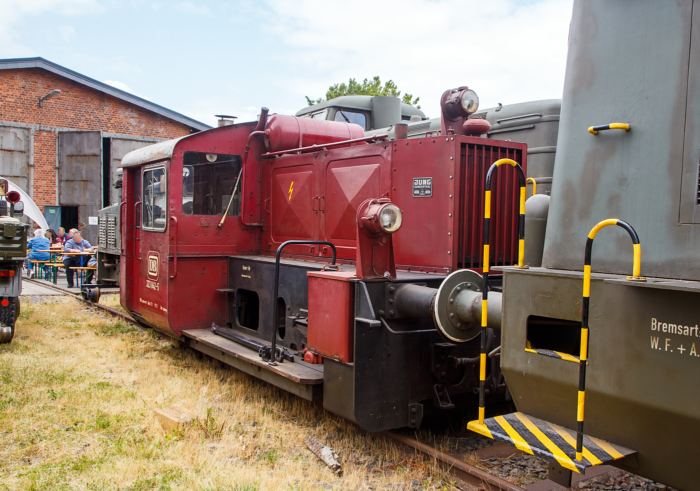 Die ex DB 323 842-5, ex DB Köf 6772, der Westerwälder Eisenbahnfreunde 44 508 e. V., ausgestellt am 02.07.2023 beim Erlebnisbahnhof Westerwald in Westerburg, hier war Lokschuppen-/Sommerfest.

Diese Köf II wurde 1960 unter der Fabriknummer 13210 bei der Lokfabrik Jung in Jungenthal bei Kirchen/Sieg gebaut und als Köf 6772 an die DB ausgeliefert. Sie war eine der 108 Maschinen der LG II, die im Rahmen der vorletzten Beschaffungsmaßnahme der DB, bei der Lokfabrik Jung-Jungenthal gebaut wurden. Zum 01. Januar 1968 erhielt sie, im Rahmen neuen EDV-Nummern, die Umzeichnung in 323 842-5.

Die 323 842-5 (Jung 13210) war ab 1960 dem BW Wetzlar zugeteilt, ab 1968 wurde das Heimatbetriebswerk das Bw Limburg / Lahn, welches zum 01.12.1991 zur Außenstelle des Bw Gießen wurde. Die Zurückstellung von der Ausbesserung (Z-Stellung) erfolgte am 22. Juli 1996 im Bw Gießen, der am 30.08.1996 die Ausmusterung (Bw Gießen) folgte. Ab 1997 stand die Lok der BSW-Gruppe Koblenz, Ortsgruppe Siershahn zur Verfügung. Nach der Gründung des Vereins Westerwälder Eisenbahnfreunde 44 508 e. V. wurde die Lokomotive im Juli 2002 vom Verein käuflich erworben. Am 29.11.2003 wurde die Maschine per Tieflader zum jetzigen Standort ins Westerburger Museum transportiert. Die Lokomotive ist betriebsfähig und verlässt von Zeit zu Zeit den Lokschuppen mit eigener Kraft.

In den Jahren 1932 - 38 beschaffte die Reichsbahn 887 Lokomotiven dieser Baureihe. Durch die Einwirkungen des Krieges stark dezimiert übernahm die spätere Bundesbahn noch 444 Exemplare und ließ, zwischen 1952 und 1965 noch 731 weitere Maschinen der Leistungsgruppe II neu bauen. Diese splitteten sich in die Baureihen 322, 323 und 324. Loks der BR 322 hatten eine Höchstgeschwindigkeit von 30 km/h, die Loks der BR323 hatten eine Höchstgeschwindigkeit von 45 km/h. Die zahlenmäßig größte Baureihe waren die Kleinloks der Baureihe 323. Dabei wurden ursprünglich zwei Gruppen unterschieden, 323 001 - 323 499 mit Deutz-Motor sowie 323 501 - 323 999 mit Kaelble-Motor. Insgesamt gab es 892 Loks der Baureihe 323.

Der Antrieb erfolgt Dieselhydraulisch, d.h. die Kraftübertragung erfolgt vom Motor auf ein Voith-Turbogetriebe und von diesem über Rollenketten auf die beiden Achsen. Die Hersteller waren Gmeinder, O&K, Krupp, KHD, BMAG, Borsig, Jung und Henschel. Die Baureihe hat ausgedient und ist nur noch vereinzelt in div. Museen anzutreffen.

TECHNISCHE DATEN:
Spurweite: 1435 mm (Normalspur)
Achsfolge : B
Länge über Puffer: 6.450 mm
Achsabstand: 2.500 mm
Treibraddurchmesser:	850 mm (neu)
größte Breite: 3.050 mm
größte Höhe: 2.890 mm
Dienstgewicht: 17 t 
Motorenart: wassergekühlter 6-Zylinder- Reihendieselmotor vom Typ Kaelble GN130 s
Leistung: 128 PS (94 kW) bei 1300 U/min.
Motorhubraum: 14,33 Liter (Bohrung 130 mm x 180 mm Hub)
Getriebe: Voith L33U
Höchstgeschwindigkeit: 45 km/h 
Anfahrzugkraft: 27,5 kN
Die Kraftübertragung vom Getriebe auf die Achsen erfolgt über Rollenketten.
