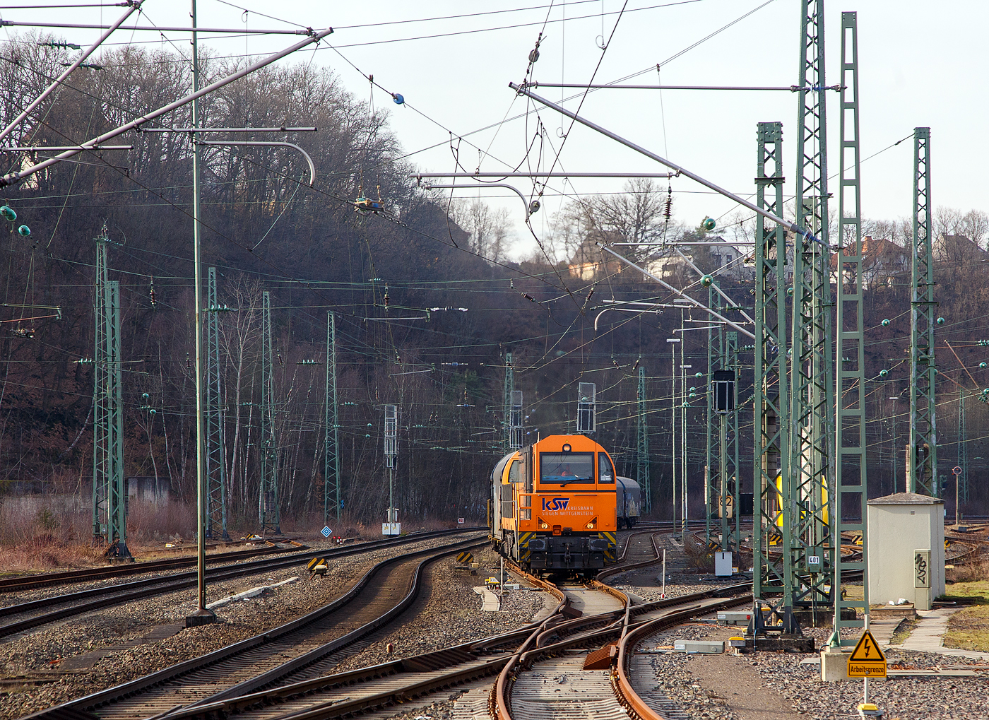 Die KSW 43 (92 80 1273 018-2 D-KSW), die asymmetrische Vossloh G 2000 BB der KSW (Kreisbahn Siegen-Wittgenstein) f�hrt am 09.02.2023, mit ihrem Coilzug (VTG Coilwagen der Gattung Shimmns-ttu), von Betzdorf (Sieg) �ber Siegen, Dillenburg und Haiger nach Herdorf, was einem Umweg von �ber 62 km bedeutet. (Aufnahme vom Bahnsteig 106)

Eigentlich w�rde der Zug hier auf die KBS 462 – Hellertalbahn abbiegen und er w�re in 7,2 km am Ziel. Aber die Hellertalbahn bleibt, nach dem Felssturz am 23.12.2022 in Herdorf bis voraussichtlich zum kleinen Fahrplanwechsel am 09. Juni 2023 gesperrt. Ein weiterer Nachteil ist das die Strecke Haiger – Herdorf nur die Streckenklasse CE hat und zudem sehr Steigungsreich ist. Die 7,2 km lange Strecke Betzdorf – Herdorf hat die Streckenklasse D4, so k�nnen die Coilwagen auch nur abgelastet zugestellt werden.

Nochmal einen lieben Gru� an den netten Lokf�hrer zur�ck.

Zudem habe ich es hier nicht verstanden, warum der KSW-Zug erst auf den Regionalverkehr warten musste bevor es weiter ging. Denn der Zug k�nnte doch ohne Halt durchfahren.
