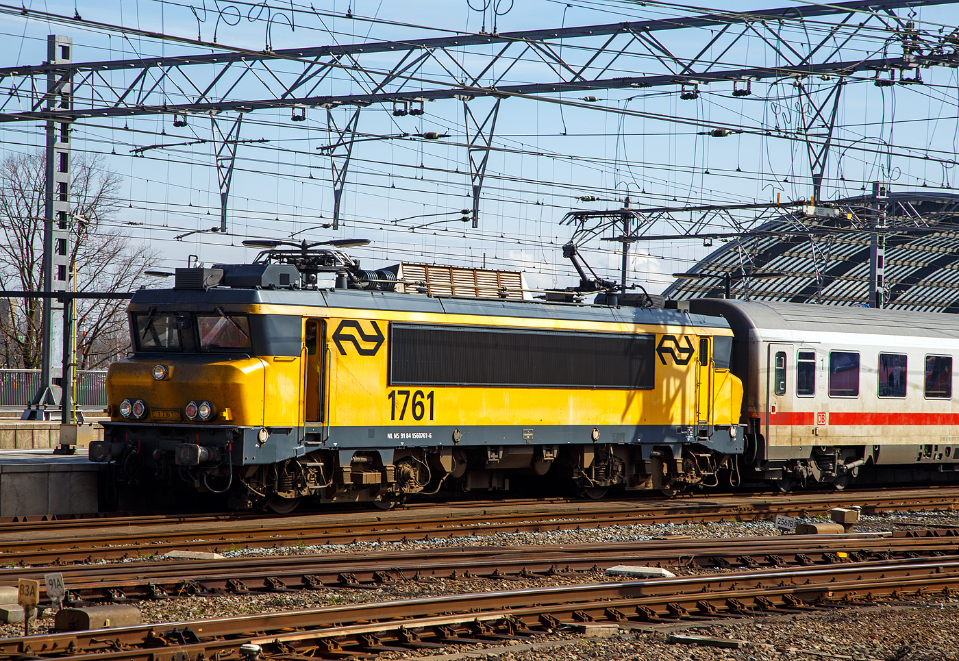 Die NS 1761 (91 84 1560761-6 NL-NS) hat am 31 M�rz 2018 mit einem EuroCity (DB IC-Wagen) den Bahnhof Amsterdam Centraal erreicht.

Bei der NS-Baureihe 1700 handelt es sich um eine vierachsige Elektrolokomotiven, zwischen 1991 und 1994 gebaut wurden. Die Loks wurden ab Anfang 1992 bei den Niederl�ndischen Eisenbahnen (NS - Nederlandse Spoorwegen) vor Reisez�gen eingesetzt. Sie basiert, wie die Schwesterbaureihe 1600/1800, auf der BB 7200 der franz�sischen Staatsbahn SNCF. Die Baureihe 1700 ist jedoch eine modernere Variante der Baureihe 1600. Sie unterscheidet sich von der Reihe 1600 durch verst�rkten Einsatz von Elektronik, eine neuere Version der ATB-Zugsicherung (Version 4 statt 3) und ein anderes Bremssystem. 

Die Lokomotiven waren bis zum 9. Dezember 2023 vor den Intercity-Z�gen zwischen Amsterdam und Berlin auf dem niederl�ndischen Abschnitt bis zum Grenzbahnhof Bad Bentheim im Einsatz. Zuvor bespannten sie Wendez�ge, die aus DD-AR- (Dubbeldeks-AggloRegiomaterieel, Agglomeration-Regionalausr�stung) und DDM-Doppelstockwagen (Dubbeldeksmaterieel, Doppelstockausr�stung) oder einst�ckigen ICRm-Wagen (Intercityrijtuig m, Intercity-Reisezug Baureihe m) bestanden.

Zum Kuppeln mit DD-AR-Wagenparks sind die Lokomotiven einseitig zus�tzlich mit einer BSI-Kompaktkupplung unter der Regelschraubenkupplung ausgestattet.

Die Wendezugsteuerung der ICRm-Steuerwagen ist nur mit den 1700 nutzbar. Die Vielfachsteuerung der Baureihe 1700 erm�glicht das Kuppeln f�r Doppeltraktion untereinander oder mit mDDM, nicht jedoch mit den Lokomotiven der Reihen 1600/1800.

Obwohl bei den Niederl�ndischen Eisenbahnen Rechtsverkehr herrscht, sitzt der Triebfahrzeugf�hrer wie bei den SNCF-Lokomotiven auf der linken Seite.

TECHNISCHE DATEN:
Spurweite: 1.435 mm
Achsformel:  B’B’
L�nge �ber Puffer: 17.640 mm
Drehzapfenabstand: 9.694 mm
Achsabstand im Drehgestell: 2.800 mm
Treibraddurchmesser: 1.250 mm (neu)
Dienstgewicht: 86,0 t
Radsatzfahrmasse: 21,5 t
H�chstgeschwindigkeit: 180 km/h (in der Praxis 140 km/h)
Stundenleistung:  4.540 kW (2x 2.270 kW)
Anfahrzugkraft: 260 kN
Stromsystem: 1,5 kV DC
Kleister befahrbarer Gleisbogen: R=50 m
