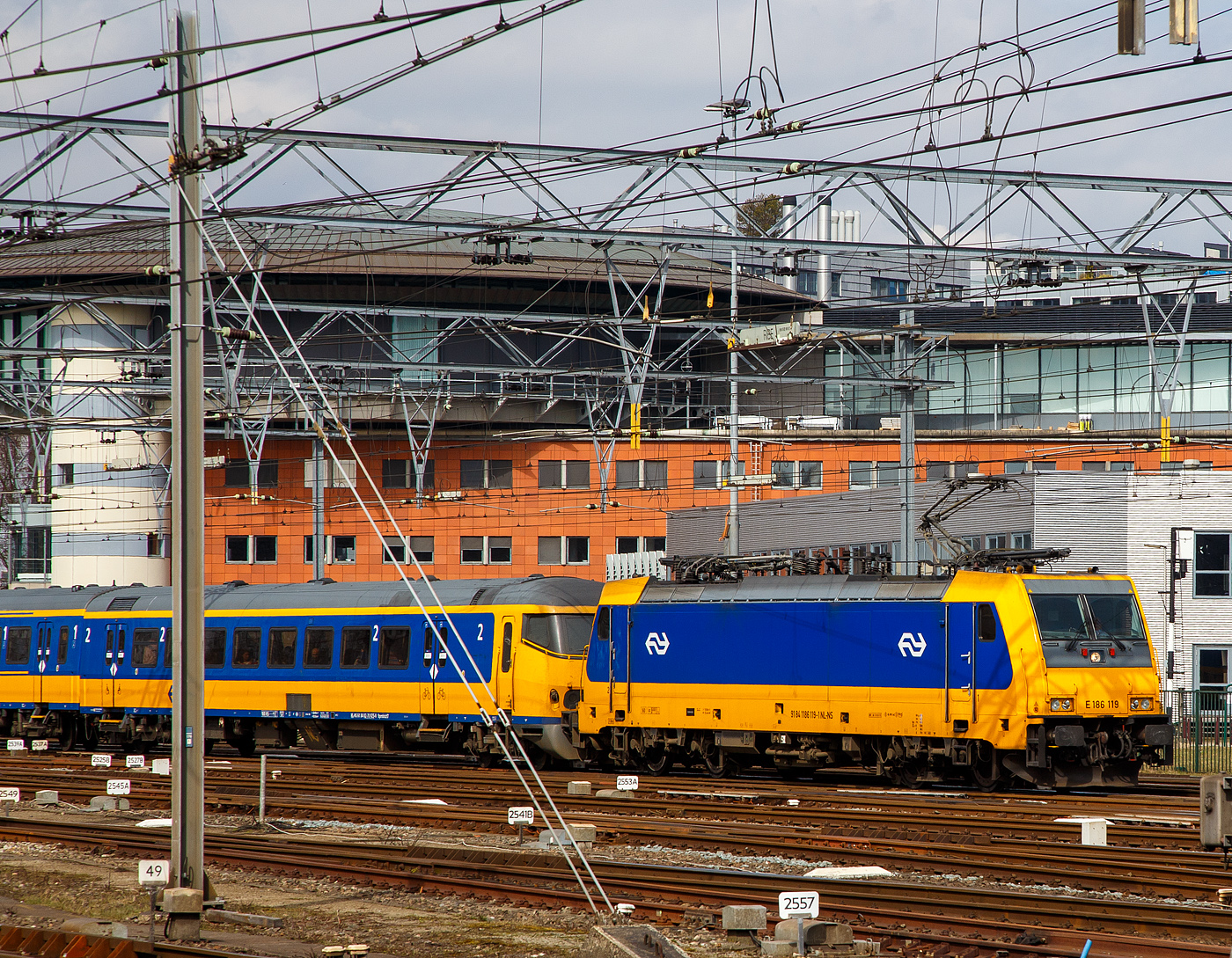 Die NS 186 119 (91 84 1186 119-1 NL-NS) erreicht am 31 M�rz 2018 mit einem IC (InterCity) den Bahnhof Amsterdam Centraal. Am Zugschluss war noch eine weitere 186er. 

Die Bombardier TRAXX F140 MS wurde 2007 von Bombardier in Kassel unter der Fabriknummer 34323 gebaut und an die ATC - Angel Trains Cargo, seit 2008 war sie dann an die NS Hispeed bzw. NS - Nederlandse Spoorwegen N.V. vermietet. Sie hat die Zulassungen f�r Deutschland, �sterreich, Belgien und die Niederlande. Aktuell (seit 2024) ist die Lok an die SNCB - Soci�t� Nationale des Chemins de Fer Belges als 2869 vermietet und tr�gt die UiC Nummer 91 84 1186 119-1 NL-B. 

Die NS-Baureihe 186 wurden von Bombardier Transportation zwischen 2006 und 2014 gebaut. Die Lokomotiven werden zum Ziehen von Personenz�gen verwendet, fr�her f�r NS Hispeed und jetzt f�r NS International. Sie sind eine Multi-Systems-Variante des TRAXX, einer Vierfach-Spannungslokomotive, die auf den meisten europ�ischen Elektrifizierungssystemen arbeiten kann: 1,5/3,0 kV DC und 15/25 kV AC.

Die BR besteht aus zwei Chargen, die erste im Jahr 2008 eingef�hrte Bauloks. Die zweite Charge wurde 2014 eingef�hrt. Die ersten 12 Lokomotiven wurden 2005 von der Hochgeschwindigkeitsallianz (HSA) bei Alpha Trains bestellt. Die Bombardier Transportation in Kassel baute und �ber Alpha Trains angemietet wurden. Diese kamen ab 2008/2009 auf den Verbindungen der HSL-Zuid zwischen Amsterdam und Breda zu Einsatz. Diese Z�ge haben eine H�chstgeschwindigkeit von 160 km/h. Diese Lokomotiven mit den Z�gen sollte nur eine tempor�re Ma�nahme sein, bis die Hochgeschwindigkeitstriebz�ge Fyra V250 (AnsaldoBreda V250) in Betrieb genommen wurden. Die V250 traten 2012 in Dienst, wurde aber Anfang 2013, wegen zahlreicher M�ngel, au�er Betrieb genommen und an den Hersteller zur�ckgegeben. Die italienische Trenitalia kaufte 2017 17 von den 19 Einheiten, die dort nun als ETR 700 im Einsatz sind. 

Aus diesem Grund waren die NS TRAXX-Lokomotiven noch bis 2024 im Einsatz.
