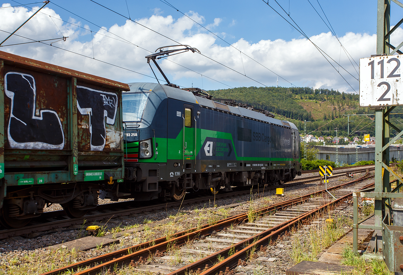 Die nun an die ecco-rail GmbH vermietete SIEMENS Vectron MS 193 258 (91 80 6193 258-1 D-ELOC) der ELL - European Locomotive Leasing (Wien) fährt am 22 Juli 2024, mit einem offen Güterzug (offene Güterwagen der Sonderbauart der Gattung Fas E78.6 der ERMEWA) durch Niederschelden in Richtung Siegen. Zwischen 2016 und 2023 war die Lok an die SBB Cargo International, was man doch noch erkennen kann. Stefan hatte sie als solche mal im Juli 2018 vor der Linse, siehe http://hellertal.startbilder.de/bild/schweiz~strecken~alte-hauensteinlinie-olten-laeufelfingen-sissach-2/619762/die-beiden-193-258-und-461.html

Die Multisystemlokomotive Siemens Vectron MS wurde 2016 von Siemens Mobilitiy in München-Allach unter der Fabriknummer 22154 gebaut.

Diese Vectron Lokomotive ist als MS – Lokomotive (Mehrsystemlok) mit 6.400 kW Leistung und 160 km/h Höchstgeschwindigkeit konzipiert. Hier in der Variante Vectron MS A 22 hat sie die Zulassungen für Deutschland, Österreich, Schweiz, Italien und die Niederlande (D/A/CH/I/NL).Die SIEMENS Vectron MS der Version A 22 besitzt die Zugsicherungssysteme ETCS BaseLine 3, sowie
für Deutschland (PZB90 / LZB80 (CIR-ELKE I)), 
für Österreich (ETCS Level 1 mit Euroloop, ETCS Level 2, PZB90 / LZB80),
für die Schweiz (ETCS Level 2, ZUB262ct, INTEGRA)
für Italien (SCMT)
und für die Niederlande (ETCS Level 1, ETCS Level 2, ATB-EGvV)

Der Lokmieter, die ecco-rail GmbH ist ein österreichisches Eisenbahnverkehrsunternehmen mit Sitz in Wien und wurde 2011 gegründet. Das Unternehmen befördert Güterzüge in Europa, hauptsächlich jedoch in Österreich und Deutschland. Das Unternehmen setzt moderne Elektrolokomotiven ein, welche von Lokomotivvermietern angemietet werden. Im Bestand sind unter anderem Lokomotiven der Baureihen 185 bzw. 187 (angemietet von Railpool), 189 (angemietet von Beacon Rail Capital Europe, ex MRCE) und 193 (angemietet von Railpool sowie ELL Austria), sowie zwei Lokomotiven vom Typ Stadler Eurodual (BR 2159) und zwei vom Typ Euro 9000 (BR 2019). Die Stadler Lokomotiven werden von European Loc Pool angemietet.