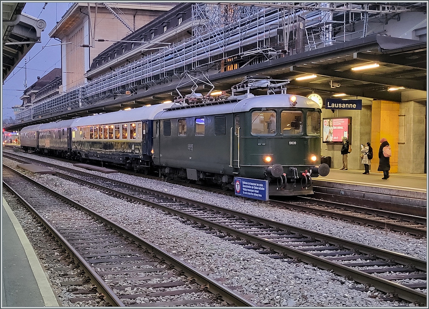 Die Re 4/4 I 10039 stellt den Extrazug 31131 in Lausanne bereit. Der Zug verkehrt für eine Reisegruppe nach Zürich Enge (mit Halt in Palézieux). Der Zug besteht aus dem  Le Salon Bleu  61 85 80-90 200-6 CH-IRSI, dem 56 80 89-80 010-2 WGm D-IRSI und dem Am 56 80 10-40 360-4 D-IRSI. Da der TEE Rheingold Genève - Amsterdam am Schluss seiner Einsatzzeit vor vielen Jahren aus einem DB Speisewagen, einem DB Abteilwagen und einen DB Großraumwagen bestand und auch von einer Re 4/4 I gezogen wurde, weckt der heutige Zug doch Erinnerungen an den TEE 6 / 7, der am 23. Mai 1982 zum letzten Mal ab Genève fuhr, (und sich dann noch gut zwei Jahre auf dem Abschnitt Basel - Amsterdam hielt). Leider die Re 4/4 I 10039 etwas ungeschickt vor dem Schild  Überschreiten der Geleise verboten, und leider waren diese Lichtverhältnisse nichts für meine kleine Knipse, so dass ich hier ausnahmsweise ein Handy-Bild zeige. 
Die Re 4/4 I gehört heute der SWISS RAIL TRAFFIC und war früher als Re 416 628 bei der Mittelthurgaubahn unterwegs und vorgängig bei den SBB mit der heute noch angeschrieben Nummer 10039 im Einsatz. Damals trug die am 22. Dez. 1950 abgelieferte Lok jedoch noch die verchromten Buchstaben SBB - CFF resp. SBB - FFS an den Seitenwänden.

11. Dezember 2024