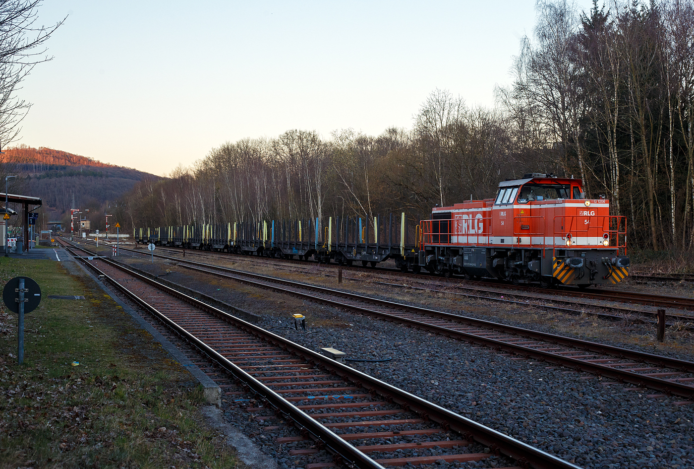 Die RLG 54 / 175 504-9 (92 80 1275 504-9 D-RLG) eine MaK G 1206 der RLG - Regionalverkehr Ruhr-Lippe GmbH (Soest), vermietet ans Schwesterunternehmen WLE - Westfälische Landes-Eisenbahn GmbH, kommt am 18. März 2025 auf ihrer Heimreise mit einem leeren Güterzug (Schwerlastwagen) von der Salzgitter Mannesmann Precision GmbH in Burbach-Holzhausen über die Hellertalbahn durch Herdorf. Hier im Bahnhof Herdorf hat sie, wegen der eingleisigen Strecke, erstmal Hp 0, bevor es in Richtung Betzdorf weitergeht.

Die G 1206 wurde 2008 von Vossloh in Kiel unter der Fabriknummer 5001638 gebaut. Sie war die erste wieder mit einen MTU gebaute G 1206. So hat sie einen wassergekühlten V12-Zylinder-Dieselmotor mit Abgasturbolader und Ladeluftkühlung vom Typ MTU mit einer Leistung von 1.500 kW (bei 1.800 U/min).

TECHNISCHE DATEN der G 1206:
Spurweite: 1.435 mm
Antriebart:  dieselhydraulisch
Achsfolge: B'B' 
Länge über Puffer: 14.700 mm
Drehzapfenabstand: 7.200 mm
Achsabstand im Drehgestell: 2.400 mm
größte Breite: 3.080 mm
Höhe über Schienenoberkante: 4.220 mm
Raddurchmesser neu: 1.000 mm
Motor: MTU 12 Zylinder 4-Takt Dieselmotor mit Abgasturbolader und Ladeluftkühlung vom Typ 12V 4000 R41
Leistung: 1.500 kW bei1.800 U/min
Strömungsgetriebe: Voith L 5r4 zseU2
Anfahrzugkraft: 267 kN
Höchstgeschwindigkeit: 100 km/h
kleinster befahrbarer Gleisbogen:	60 m
Dienstgewicht: 88 t
Kraftstoffvorrat: 3.150 l