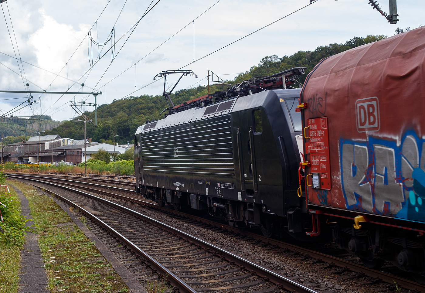 Die schwarze 189 091-2 (91 80 6189 091-2 D-DB, Class 189- VJ) der DB Cargo AG, MRCE Dispolok ES 64 F4-991, fährt am 11 September 2024, mit einem Coilzug (sechsachsigen Drehgestellflachwagen mit verschiebbarem Planenverdeck und Lademulden für Coils, der Gattung Sahimms-tu 900.2), durch den Bahnhof Scheuerfeld (Sieg) in Richtung Betzdorf bzw. Siegen.

Die SIEMENS EuroSprinter ES 64 F4 wurde 2005 von Siemens in München-Allach unter der Fabriknummer 21077 gebaut und in der Variante B, an die damalige Railion Deutschland AG ausgeliefert und war nur für Deutschland zugelassen. Im Jahr 2006 wurde sie an die MRCE Dispolok verkauft, wo sie die Bezeichnung ES 64 F4-991 (91 80 6189 091-2 D-DISPO) trug. 2008 wurde sie dann in die Variante J umgebaut und hat so nun die Zulassungen für Deutschland und die Niederlande. Unteranderem war sie an die ERSR, LTE, RRF und die SBB Cargo International AG vermietet. Im November  2021 wurde sie dann an die DB Cargo AG verkauft.

Die BR 189 (Siemens ES64F4) hat eine Vier-Stromsystem-Ausstattung, diese hier hat die Variante J (Class 189-VJ) und besitzt so die Zugbeeinflussungssysteme LZB/PZB, ETCS und ATB für den Einsatz in Deutschland und den Niederlanden.
Die Stromabnehmerbestückung ist folgende:
Pos. 1: D, NL (AC)
Pos. 2: NL (DC)
Pos. 3: NL (DC)
Pos. 4: D, NL (AC)