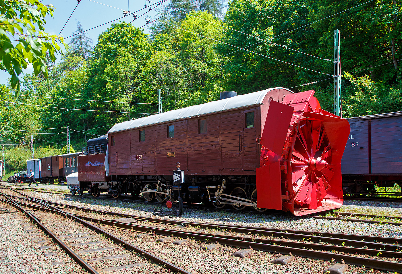 Die Selbstfahrende Dampfschneeschleuder R 1052 (ex Berninabahn) BB R 1052, ex RhB R 14, ex RhB Xrot d 9214), der Museumsbahn Blonay-Chamby, hier am 27.05.2023 auf dem Museums-Areal der (BC) in Chaulin.

Die Schneeschleuder wurde 1912 von der Schweizerischen Lokomotiv- und Maschinenfabrik (SLM) unter der Fabriknummer 2299 als R 1052 für die Berninabahn gebaut, 1944 um bezeichnet in RhB R 14, 1954 um nummeriert in RhB Xrot d 9214 (Die Bezeichnung Xrot d setzt sich zusammen aus: X = Dienstfahrzeug, rot = rotierend, d = dampfgetrieben.), 1990 ging sie an die DFB, 1996 wurde sie im Tausch gegen die ehemalige RhB R 12 von der B-C übernommen.

Dieses Fahrzeug wie auch das heute noch bei der RhB betriebsfähige Schwesterfahrzeug Xrot d 9213 (ex BB R 1051) sind dampfgetriebene Schneeschleudern mit eigenem Antrieb die für die Berninabahn (BB) gebaut wurden, die seit 1944 zur Rhätischen Bahn gehört. Im Gegensatz zu den bisher gebauten Fahrzeugen, auch der zwei Dampfschleudern der RhB-Stammstrecke, handelt es sich bei den beiden Bernina-Schleudern um selbstfahrende Fahrzeuge. Die Berninabahn entschied sich hierzu, weil in den engen Kurven mit nicht genügend hoher Kraft geschoben werden konnte und die Bahn selbst keine Fahrdraht-unabhängigen Triebfahrzeuge besaß. Die Schleudern wurden dennoch normalerweise mit Schiebetriebfahrzeugen eingesetzt, damit die gesamte Kesselleistung für die Dampfmaschine des Schleuderrades zur Verfügung stand.

Mit der Übernahme der Berninabahn durch die Rhätische Bahn (RhB) erhielten die beiden Schleudern die neuen Bezeichnungen R 13 und R 14, 1950 dann Xrot d 9213 und 9214. Die beiden Fahrzeuge befanden sich bis 1967 im regelmäßigen Einsatz und wurden danach durch modernere Schleudern ersetzt. Die Xrot d 9213 wird von der RhB im Heimatdepot in Pontresina weiterhin betriebsfähig gehalten. Sie wird heute vor allem zu touristischen Zwecken noch betrieben, und zwar im Rahmen so genannter Fotofahrten; zuweilen kommt sie aber auch noch bei der Räumung zum Einsatz.

Die Achsformel ist C'C', das Fahrzeug verfügen nach Bauart Meyer über zwei dreiachsige Triebdrehgestelle die durch vier Zylinder angetrieben werden, diese befinden sich unten mittig zwischen den Triebgestellen, darüber befindet sich der Antrieb für die Schneeschleuder, die von zwei weiteren Zylindern angetrieben wird. Der Durchmesser des Schleuderrads beträgt 2,5m, welches mit bis zu 170 U/min dreht und so bis zu drei Meter hohe Schneemassen beseitigen kann.
Gekuppelt ist die Schneeschleuder mit einem zweiachsigen Tender.

Die Xrot d 9214 wurde am 26. Januar 1968 zu einem einmaligen Großeinsatz auf der Arosabahn herangezogen. Geschoben von zwei ABDe 4/4 hatte sie die tiefverschneite Strecke zwischen Langwies und Arosa zu räumen und benötigte für den nur acht Kilometer langen Abschnitt acht Stunden.

TECHNISCHE DATEN:
Gebaute Anzahl: 2 (BB 1051, BB 1052)
Hersteller: SLM
Baujahre: 1910 und 1912
Ausmusterung: 1967 (1052/ 9214), Die 1051 ist als RhB Xrot d 9213 betriebsfähig
Spurweite: 1.000 mm (Meterspur)
Achsformel: C'C'
Länge: 13.865 mm
Höhe: 3.800 mm
Breite: 2.800 mm, max. 3.600 mm
Gesamtradstand: 10.655 mm (inkl. Tender)
Kleinster befahrbarer Gleisbogen: R=45 m
Dienstgewicht: 45 t
Dienstgewicht mit Tender: 63,5 t
Höchstgeschwindigkeit: 35 km/h
Indizierte Leistung Antrieb: 221 kW
Indizierte Leistung Schneeschleuder: 368 kW
Treibraddurchmesser: 750 mm
Zylinderanzahl: 4 für Antrieb und 2 für Schneeschleuder
Kesselüberdruck: 14 bar
Wasservorrat: 7 m³
Kohlevorrat: 4 t