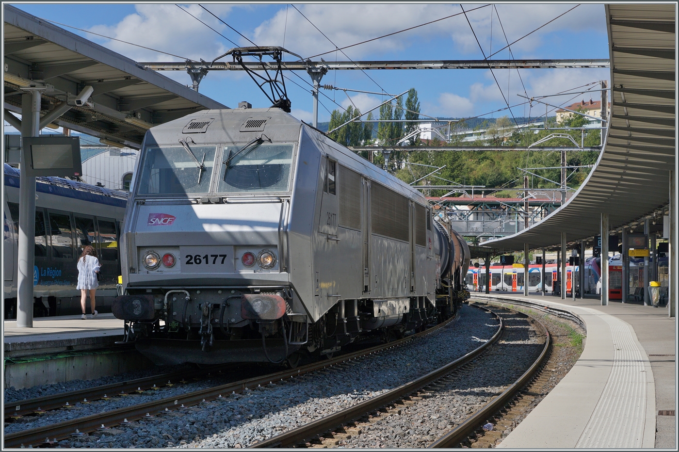 Die SNCF BB 26177 wartet mit ihrem kurzen Güterzug in Bellegarde (Ain) auf die Weiterfahrt nach Genève La Praille. Der Zug besteht aus folgenden Güterwagen: dem Zancn 33 RIV 80 D-VTG 7929 200-3 (Gefahrenanschrift 80 1789), dem Zces 23 RIV 85 CH VTGCH 7376 622-3 (80 1830), dem Uacns 37 TEN 80 D GATXD 9326 526-7 (X423 1402), dem Zacns 37 RIV 80 D VTGCH 784 6 346-0 (80 1824) dem Zacns 33 RIV 87 F ERSA 7929 952-2 (80 1824) und dem 33 TEN 80 D VTG 7834 837-2, also alles Kesselwagen mit wohl mehr oder weniger griffigem Ladegut.

26. August 2024