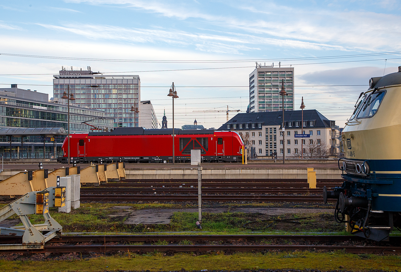 Diese Lokomotivbaureihe wird man bald auf deutschen Gleisen wohl öfters sehen können. Denn die DB Cargo erneuert seine Rangier- und Strecken-Lokflotte und beschafft neue Zweikraftlokomotiven der BR 248, als Ersatz für die älteren Diesellokomotiven der Reihe 294 (V 90). Es wurde Rahmenvertrag mit dem Hersteller Siemens Mobility über bis zu 400 Fahrzeuge, die einem Investitionsvolumen von deutlich über einer Milliarde Euro entsprechen, angeschlossen. Geliefert werden Lokomotiven vom Typ Vectron Dual Mode mit spezifischen Anpassungen für das von DB Cargo geplante Einsatzspektrum. Zunächst bestellt die DB Cargo 100 Loks der Baureihe 248. Die Auslieferung startet ab 2023. Die DB Loks sind aber stark modifiziert, so soll bei ihnen die Achslast maximal 21 t betragen (statt 22,5 t). Sie erhalten in den Führerständen einen zusätzlichen Seitenfahrschalter und einem Mikrofon statt des gewohnten Seitenfensters versehen. 

Hier fährt am 08.12.2022, die sehr neue (Baujahr 2022) Siemens Vectron Dual Mode 248 999-5 (90 80 2248 999-5 D-SIEAG) der Siemens Mobility GmbH (evtl. Vorführmaschine) durch den Hauptbahnhof Dresden in westlicher Richtung.

Die Vectron DM wurden 2022 von Siemens Mobility GmbH in München-Allach unter der Fabriknummer 23166 gebaut.

Der Vectron Dual Mode vereint die Vorteile einer vollwertigen Diesellokomotive mit denen von elektrischen Lokomotiven. Dank des leistungsstarken Dieselantriebs sowie der Ausstattung für die Nutzung der Fahrleitung kann man jederzeit flexibel auf die Traktionsanforderungen reagieren. So bleibt man immer in Bewegung, egal ob mit oder ohne Fahrdraht. Wo ein Fahrdraht ist, sollte man ihn nutzen. Denn der Betrieb unter Oberleitung ist im Vergleich zum Dieselbetrieb deutlich kosteneffizienter und umweltfreundlicher. Doch weil es in Deutschland noch lange Zeit Strecken geben wird, die nicht vollständig elektrifiziert sind, fahren viele Diesellokomotiven unter Fahrdraht weiter. Das ist aber ökonomisch und ökologisch wenig sinnvoll. Dies ist hier ein Beispiel einer echten Alternative. 

Mit der Vectron Dual Mode ist es möglich Güterzüge aus dem Umland umweltschonend in die Zentren der Ballungsräume zu befördern. Nur so einfach, wie in der Siemens Werbung ist es auch nicht, denn die Lok vier Achsen (Bo’Bo’) und wiegt 90 t, so ergibt sich eine Achslast  von 22,5 t. Nicht elektrifizierte Nebenstrecken haben nicht gerade alle von min. D2 (22,5 t), und können so auch nicht befahren werden. Auch die Leistung der DM im Vergleich zu heutigen Hochleistungselektrolokomotiven ist mit 2.400 kW erheblich geringer. Mit den Dieselstreckenloks kann sie aber mit 2.000 kW sehr gut mithalten, zudem liegt die Anfahrzugskraft bei stattlichen 300 kN.

TECHNISCHE DATEN der Siemens Vectron Dual Mode (BR 248)
Spurweite: 1.435 mm
Achsformel: Bo'Bo'
Länge über Puffer: 19.975 mm
Drehzapfenabstand: 10.800 mm
Achsabstand im Drehgestell: 2.700 mm
Breite: 3.020mm
Höhe:  4.220 mm
Raddurchmesser :  1.100 mm (neu) / 1.020 mm (abgenutzt)
Gewicht:  90 t (bei vollen Vorräten)
Achslast: 22,5 t
Spannungssysteme (bei E-Betrieb): 15 kV, 16,7 Hz
Dieselmotor: MTU 16V 4000 R84 (16-Zylinder-V-Motor)
Dieselmotorleistung an der Kurbelwelle: 2.400 kW
Max. Leistung am Rad: 2.400 kW bei E-Antrieb / 2.000 kW bei D-Antrieb
Höchstgeschwindigkeit:160 km/h
Antriebsart: elektrisch oder dieselelektrisch
Kraftübertragung :Teilabgefederter Antrieb (Ritzelhohlwellenantrieb)
Kraftstoffbehälter Nutzvolumen: 2.600 l
Anfahrzugskraft:  300 kN
Elektrische Bremskraft: 150 kN
Elektrische Bremsleistung (am Rad): E-Betrieb 2.100 kW / Dieselbetrieb 1.700 kW
Doppeltraktion: Über WTB ÖBB mit typgleichen Fahrzeugen sowie Vectron E, Vectron DE und ER20
Zugsicherung: PZB / für ETCS vorbereitet
