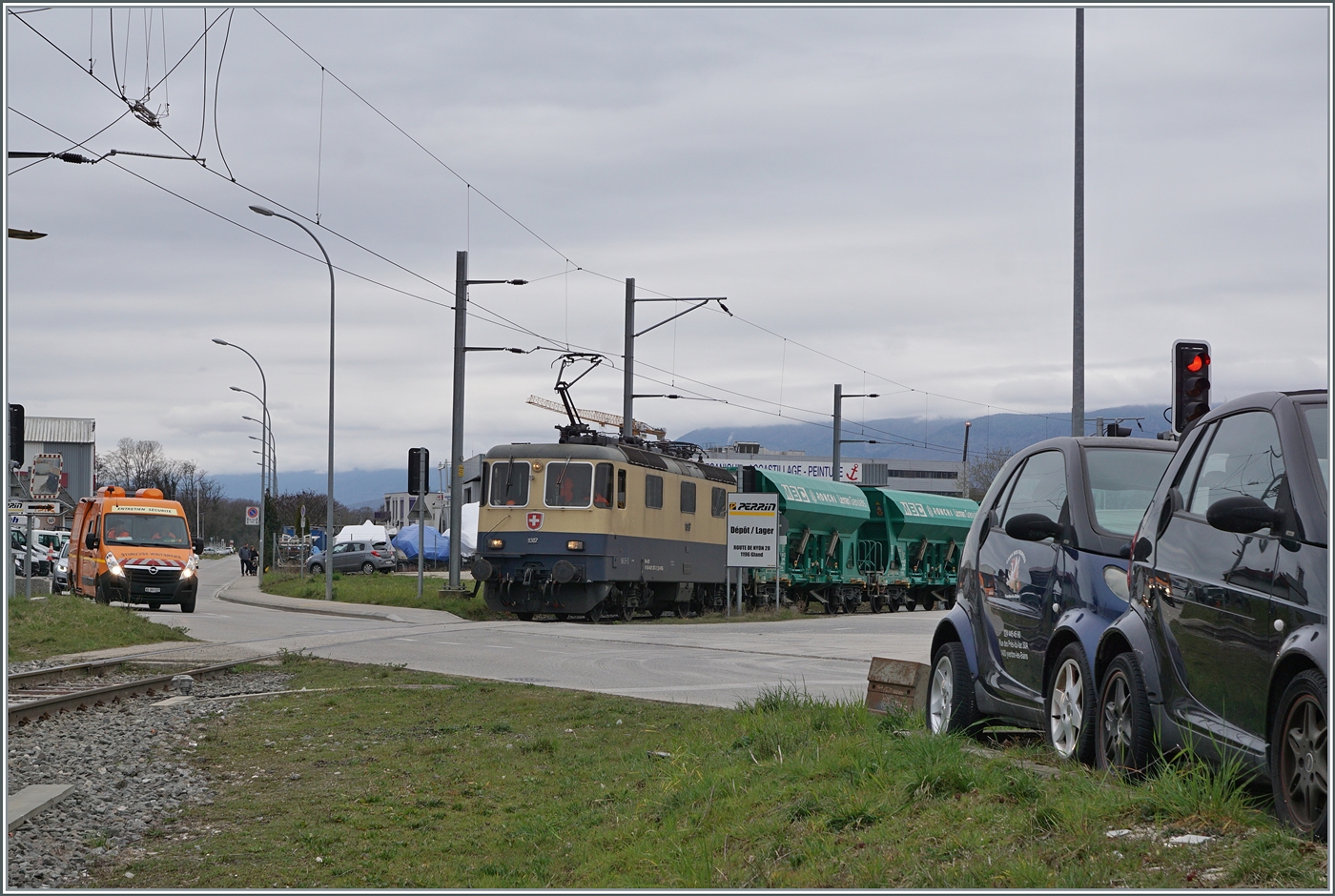 Diese Übersichtsbild zeigt, dass ich beim vorherigen Bild NICHT mitten auf dem Gleis stand, sondern auf der Strasse, die zum Zeitpunkt der Aufnahme nicht für den Autoverkehr gesperrt war. Hier hingegen waren die Autos, damit die IRSI/IGE  Rheingold  Re 4/4 II 11387 (Re 421 387-2) mit ihrem Kieszug zum Bahnhof von Gland fahren kann (und dies mit sehr geringer Geschwindigkeit).

4. März 2024