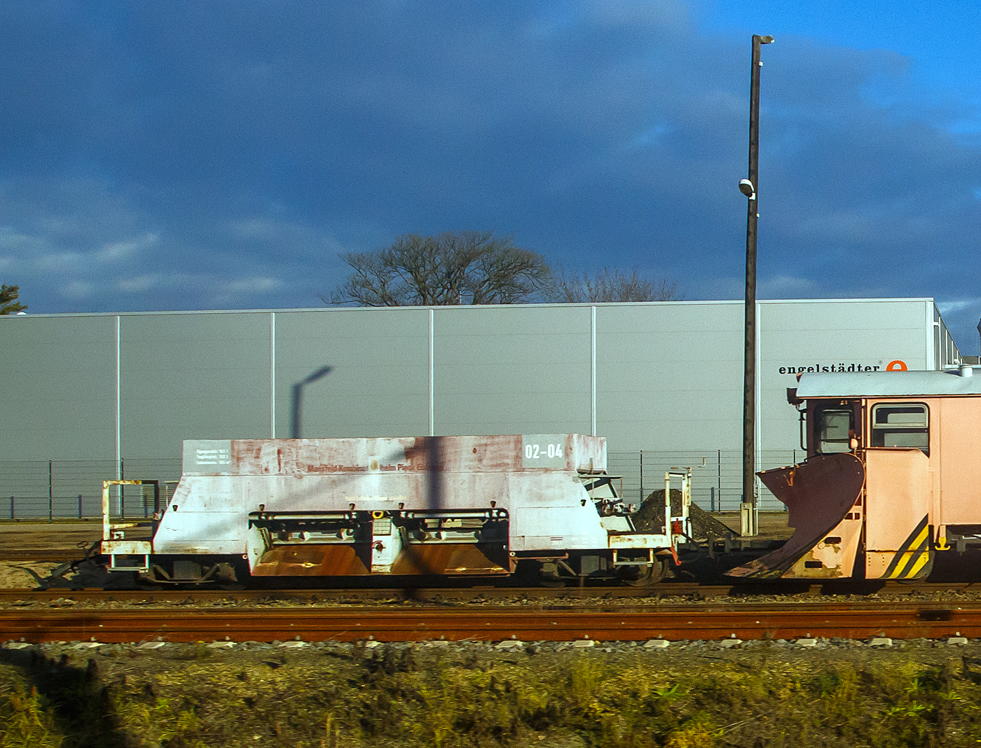 Ehemaliger vierachsiger Schmalspur (750 mm) Rohsteinwagen 02-04 der VEB Mansfeld Kombinat Wilhelm Pieck Eisleben (heute MBB - Mansfelder Bergwerksbahn), nun wohl als 4-achsiger Seitenentlade-Schotterwagen der L��nitzgrundbahn (zur SDG - S�chsische Dampfeisenbahngesellschaft mbH), angestellt am 08.12.2022 in Radebeul Ost, aufgenommen aus einem IC).

Seit dem Ende des Kupferbergbaus werden diese Wagen nur noch in historischen G�terz�gen zum Transport von Rohsteinen verwendet. Da sie sich aber gut f�r den Transport von Schotter eignen und ihn zugleich auch an die richtigen Stellen platzieren k�nnen, sind sie oft f�r die Unterhaltung der Strecken im Einsatz. Deswegen machen auch andere Bahnen (wie hier die SDG) gern von diesem Wagentyp Gebrauch.

Diese Wagen wurden 1953 vom VEB Waggonbau Gotha, die zur Vereinigung Volkseigener Betriebe Lokomotiv- und Waggonbau (VVB LOWA) geh�rte, f�r die Mansfelder Bergwerksbahn gebaut.

TECHNISCHE DATEN:
Bezeichnung : Sch�ttgutwagen / Bauart Sattelboden-Selbstentlader
Spurweite: 750 mm
Anzahl der Achsen: 4 (in 2 Drehgestellen)
L�nge �ber Kupplung: 9.400 mm
Drehzapfenabstand: 6.300 mm 
Breite: 2.000 mm 
Auswurfbreite:1.600 mm (800 mm von Greismitte)
Achsanstand im Drehgestell: 1.320 mm
Laufraddurchmesser: 600 mm (neu) 
Eigengewicht: 10.500 kg
Max. Ladegewicht: 20.000 kg
Max. Achslast: 7,5 t
Ladevolumen: 10,0 m�
L�nge der Belade�ffnung: 8.000 mm
Kleinster befahrbarer Gleisbogen: R = 60 m
Bremse: Druckluftbremse Knorr / Handbremse

