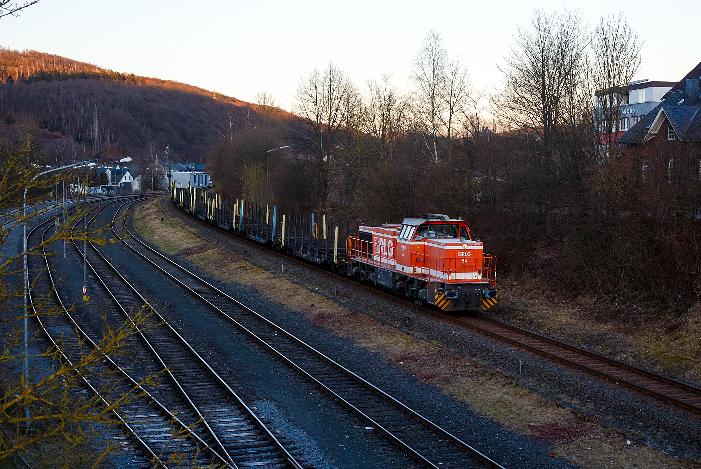 Eigentlich wollten wir nur noch im St�dtchen was Einkaufen, aber dann sah ich das Signal Hp 2….
Die RLG 54 / 175 504-9 (92 80 1275 504-9 D-RLG) eine MaK G 1206 der RLG - Regionalverkehr Ruhr-Lippe GmbH (Soest), vermietet ans Schwesterunternehmen WLE - Westf�lische Landes-Eisenbahn GmbH, kommt am 18. M�rz 2025 auf ihrer Heimreise mit einem leeren G�terzug (Schwerlastwagen) von der Mannesmann Precision Tubes GmbH in Burbach-Holzhausen �ber die Hellertalbahn durch Herdorf.

Die G 1206 wurde 2008 von Vossloh in Kiel unter der Fabriknummer 5001638 gebaut. Sie war die erste wieder mit einen MTU gebaute G 1206. So hat sie einen wassergek�hlten V12-Zylinder-Dieselmotor mit Abgasturbolader und Ladeluftk�hlung vom Typ MTU mit einer Leistung von 1.500 kW (bei 1.800 U/min).

TECHNISCHE DATEN der G 1206:
Spurweite: 1.435 mm
Antriebart:  dieselhydraulisch
Achsfolge: B'B' 
L�nge �ber Puffer: 14.700 mm
Drehzapfenabstand: 7.200 mm
Achsabstand im Drehgestell: 2.400 mm
gr��te Breite: 3.080 mm
H�he �ber Schienenoberkante: 4.220 mm
Raddurchmesser neu: 1.000 mm
Motor: MTU 12 Zylinder 4-Takt Dieselmotor mit Abgasturbolader und Ladeluftk�hlung vom Typ 12V 4000 R41
Leistung: 1.500 kW bei1.800 U/min
Str�mungsgetriebe: Voith L 5r4 zseU2
Anfahrzugkraft: 267 kN
H�chstgeschwindigkeit: 100 km/h
kleinster befahrbarer Gleisbogen:	60 m
Dienstgewicht: 88 t
Kraftstoffvorrat: 3.150 l