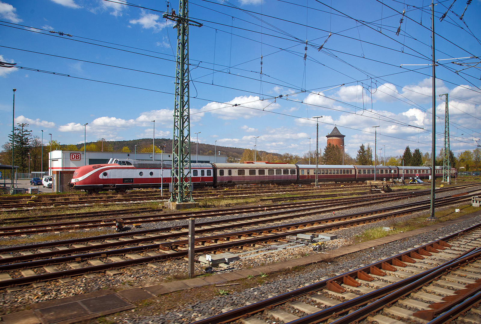 Ein einstiger Paradezug der Deutschen Bundesbahn der 1950/60er Jahre....
Der sechsteilige ehemalige TEE (Trans-Europ-Express-Verkehr) VT 11.5 / VM 11.5 der Deutschen Bundesbahn, ab 1968 DB BR 601 / 901 steht am 21.04.2023 beim DB BW Lichtenfels, aus einem fahrenden Zug heraus (durch die Scheibe) fotografiert. Leider ist der Zug in einem mäßigen Zustand, und könnte viel neue Farbe vertragen.  

Der hier sechsteilige Triebzug besteht aus:
Verbrennungsmotortriebkopf VT 11 5013, später DB 601 013-6, Baujahr 1957 unter Fabriknummer 140492 von der M.A.N. - Maschinenfabrik Augsburg Nürnberg AG (Nürnberg).
Abteilwagen VM 11 5107, später DB 901 107-3 (Hersteller LHB)
Großraumwagen  VM 11 5201, später DB 901 201-4  (Hersteller LHB)
Bar-/Speisewagen VM 11 5303, später DB 901 303-8 (Hersteller WEGMANN, Fabriknummer 3625)
Küchenwagen DB 901 502-5 (Baujahr 1963)	
Verbrennungsmotortriebkopf VT 11 5019, später DB 601 019-3, Baujahr 1957 unter Fabriknummer 140498 von der M.A.N. - Maschinenfabrik Augsburg Nürnberg AG (Nürnberg).

Ab 2001 bestand die Hoffnung auf den Wiederaufbau und Wiederinbetriebnahme eines TEE-Exemplars der Baureihe VT 11.5 durch die Deutsche Bahn. Die Kosten der Restaurierung stiegen jedoch auf bis fünf Millionen Euro, unter anderem wegen der heutigen Sicherheitsstandards (für Notausstiege, nichtentflammbare Teppichböden usw.), sodass das Projekt gestoppt wurde.

Die Baureihe VT 11.5 (BR 601/901) war ein Dieseltriebzug der Deutschen Bundesbahn (DB). Er war eine bedeutende Entwicklung im deutschen Schienenfahrzeugbau der 1950er Jahre und ein Paradezug der Deutschen Bundesbahn. Mit der Einführung des EDV-Baureihenschemas der DB im Jahr 1968 wurden die Triebköpfe (Maschinenwagen) zur Baureihe 601, die Mittelwagen zur Baureihe 901.

Tans-Europ-Express (TEE):
Für den internationalen Trans-Europ-Express-Verkehr (TEE) mit einem erhöhten Komfort wurde in Deutschland der VT 11.5 entwickelt. Im Jahre 1957 lieferten MAN 19 Triebköpfe, Linke-Hofmann-Busch 16 Abteilwagen und 8 Großraumwagen, Wegmann & Co. 8 Speisewagen mit Speiseraum, Bar und Reiseabteil sowie 9 Küchenwagen mit vollelektrischer Küche und einem weiteren Speiseraum. 1958 wurden vier und 1963 drei Abteilwagen von LHB nachgeliefert. Im hinteren Teil der Triebköpfe befanden sich ein kleiner Gepäckraum sowie zwei Dienstabteile für Zugpersonal und Zoll oder ein Zugsekretariat. Damit wurden planmäßig siebenteilige Triebzüge mit 122 Sitzplätzen sowie 46 Plätzen in den Speiseabteilen gebildet, welche 130 m lang waren und eine Gesamtgewicht von 230 t besaßen. Diese Züge bestanden aus je einem Maschinenwagen an den Zugenden, zwei Abteilwagen, einem Großraumwagen, einem Speisewagen und einem Küchenwagen. Maximal möglich waren zehnteilige Triebzüge.Das Design der Züge entwickelte der deutsche Architekt und Industriedesigner Klaus Flesche, langjähriger Leiter der Abteilung Industrial Design der MAN.

Die Züge waren für Deutschland, Niederlande, Belgien, Frankreich, Schweiz, Österreich und Italien ausgerüstet und zugelassen. Dies entsprach dem TEE-Netz in seiner ursprünglichen Ausdehnung. Ab 1957 folgte der Einsatz der Baureihe VT 11.5 im TEE-Verkehr. Damit wurden anfangs täglich fünf Triebzüge benötigt und folgende internationale Verbindungen gefahren:

    TEE 31/32 Rhein-Main Frankfurt/M–Amsterdam
    TEE 74/75 Saphir Dortmund–Oostende
    TEE 77/78 Helvetia Hamburg-Altona–Zürich
    TEE 168/185 Paris-Ruhr Dortmund–Paris Nord

Teilweise wurden die Züge mit Doppeleinheiten des VT 11.5 gefahren, aber auch mit dem VT 08 gekuppelt. Zur Kapazitätserweiterung wurden die siebenteiligen Einheiten zu zehnteiligen Triebzügen verlängert. Das ständig zunehmende elektrifizierte Streckennetz sowie die beschränkte Kapazität der Dieseltriebzüge führten Mitte der 1960er Jahre immer mehr zu einer Umstellung der internationalen TEE-Züge auf mit Lokomotiven bespannte Züge.

Intercity (IC):
Mit der Einführung des Systems InterCity ’71 wurden die TEE-Züge darin integriert. Als letzte deutsche TEE-Verbindung existierte bis 1972 (TEE 17/18 „Mediolanum“ München–Mailand)

1971 führte die Deutsche Bundesbahn den Intercity (IC) als eigenständige Zuggattung mit Erste-Klasse-Fahrzeugen im Zwei-Stunden-Takt ein. Dafür wurde die zulässige Höchstgeschwindigkeit der Baureihe 601/901 bei siebenteiligen Einheiten auf 160 km/h erhöht. Im Schnitt wurden täglich sechs Einheiten eingesetzt. Um mehr Platz zu schaffen, wurden 1976 die Barwagen zu Großraumwagen umgebaut. Um zehnteilige Einheiten mit 256 Sitzplätzen und einer Höchstgeschwindigkeit von 160 km/h betreiben zu können, wurde in vier Triebköpfen an Stelle des Dieselmotors eine Gasturbine mit einer Leistung von 2.200 PS eingebaut. Diese Triebköpfe wurden zur Baureihe 602 umgezeichnet. Aufgrund technischer Probleme wurden die Gasturbinentriebköpfe Baureihe 602 bereits 1978 ausgemustert. Mit der Einführung des neuen Intercity-Systems ’79 – „jede Stunde, jede Klasse“ – endete der Einsatz der Baureihen 601/901 im IC-Verkehr.

Technik:
In jedem originalen Triebkopf befindet sich ein schnelllaufender Zwölfzylinder-Fahrdieselmotor 12V 538 TA 10 von MTU (Motoren- und Turbinen-Union Friedrichshafen) mit 1.100 PS Leistung. Dieser entspricht dem Maybach-Motor vom Typ MD 650/1B, die Motoren unterscheiden sich lediglich in der Bezeichnung nach der Maybach- oder MTU-Nomenklatur. Ursprünglich standen auch leistungsgleiche Dieselmotoren von Daimler-Benz (MB 820 Bb) oder  MAN (L 12 V 18/21) zur Verfügung. Der VT 11.5 hatte eine hydraulische Kraftübertragung mit Getrieben wahlweise von Voith (Typ LT 306r) oder von Maybach (K104 US/W), die dem Zug zu einer Höchstgeschwindigkeit von 140 km/h verhalfen, die später auf 160 km/h angehoben wurde. Angetrieben wurde das Drehgestell unter dem Motor. Die Bremsen waren Druckluft-Scheibenbremsen ergänzt mit einer Magnetschienenbremse. Beide Triebköpfe arbeiteten parallel. Durch eine elektrische Vielfachsteuerung konnten bis zu zwei weitere Triebzüge gefahren werden. Die Steuerung war mit der der Baureihe VT 08 kompatibel. Für die Stromversorgung, unter anderem der Klimaanlagen und des Küchenwagens, war in jedem Triebkopf außerdem ein Achtzylinder-Hilfsdieselmotor der Motorenwerke Mannheim (MWM) mit einer Leistung von 232 PS (mit Aufladeturbine 296 PS) eingebaut. Dieser war mit einem Drehstromgenerator verbunden. Wenn der Hilfsdiesel nicht lief, musste der Triebkopf an eine stationäre Stromversorgung angeschlossen werden. Der Wasserkreislauf sollte nicht unter 30 °C auskühlen.

Mittelwagen:
Die Mittelwagen wurden als VM 11 5101–5123 (A 4ü, Abteilwagen mit Seitengang), VM 11 5201–5208 (A 4y, Großraumwagen mit Mittelgang), VM 11 5301–5308 (AR 4y, Speisewagen mit Barraum) und VM 11 5401–5409 (WR 4y, Küchenwagen mit Speiseraum) bezeichnet, ab 1968 entsprechend als 901 101–123, 201–208, 301–308 und 401–409. Die Abteilwagen hatten sechs Abteile mit einer Tiefe von 2.200 mm mit sechs Plätzen. Die Großraumwagen hatten 33 Plätze in 2+1-Bestuhlung, außer den Sitzen an den Stirnwänden, waren die Sitze in oder gegen die Fahrtrichtung drehbar. Charakteristisch waren die schmalen Fenster der Großraumwagen, wobei jede Sitzreihe ihre jeweils eigenen Fenster links und rechts hatte. Der Barwagen hatte sieben Plätze im Barraum, 23 Plätze im Speiseabteil und 17 Plätze im Großraumabteil jeweils in 2+1-Bestuhlung mit gegenüberliegenden Sitzen. Auch der Küchenwagen hatte 23 Plätze. Die Wagen, außer dem Barwagen, hatten an einem Wagenende einen Einstieg, die Abteilwagen eine und der Großraumwagen zwei Toiletten. Sämtliche Mittelwagen besaßen eine eigene Klimaanlage.

Die Abteil- und Großraumwagen fertigte Linke-Hofmann-Busch (LHB) in Salzgitter-Watenstedt, die Speisewagen mit Bar und Küchenwagen mit Speiseraum fertigte Wegmann & Co. in Kassel.

Baureihe 602 (Gasturbinenvariante):
Bei vier Maschinenwagen wurden Anfang der siebziger Jahre bei MAN in Nürnberg die Fahrdieselmotoren durch Gasturbinen von AVCO-Lycoming (Typ TF35) mit einer Leistung von jeweils 1.617 kW (2.200 PS) ersetzt und die VT dann in die Baureihe 602 um bezeichnet. Die Gasturbinen lieferte die Klöckner-Humboldt-Deutz  (KHD), die ja von 1872–1921 Gasmotoren-Fabrik Deutz AG hieß. Äußerlich lässt sich die Gasturbinenvariante leicht an den deutlich vergrößerten Lufteinlässen erkennen. Wegen des höheren Verbrauchs wurden die Kraftstofftanks auf 5.000 Liter vergrößert. Die vier Triebköpfe wurden im Intercity-Verkehr eingesetzt. Der planmäßige Betrieb begann im Juli 1974, als die Intercity-Verbindung „Sachsenroß“ zwischen Hamburg und Ludwigshafen auf einen Triebzug mit zwei Triebköpfen der Baureihe 602 umgestellt wurde. Ab Januar 1975 war es dann mit einer von BBC neu entwickelten Angleichssteuerung für den Zusammenlauf von Gasturbinen- und Dieseltriebkopf möglich, die Triebzüge im gemischten Betrieb mit den Baureihen 601 und 602 zu fahren. Im Regelfall waren im Planbetrieb drei Triebköpfe im gemischten Betrieb im Einsatz und einer blieb als Reserve.

Im April 1975 stellte ein Zug, bestehend aus zwei Triebköpfen der Baureihe 602 und zwei Zwischenwagen, zwischen Celle und Uelzen mit 217 km/h einen neuen deutschen Geschwindigkeitsrekord für Brennkraftschienenfahrzeuge auf. Dieser wurde im Januar 2000 durch einen ICE TD mit 222 km/h überboten. Nach Problemen mit den Gasturbinen und aus Wirtschaftlichkeitsgründen wurde die Baureihe 602 (genau wie die Gasturbinenlokomotiven der Baureihen 210 und 219) zwischen Februar 1978 und Juli 1979 mit dem Erreichen der Revisionsfristen ausgemustert.

TECHNISCHE DATEN einer siebenteiligen Einheit:
Gebaute Anzahl: 19 Triebköpfe
Hersteller: 	MAN (Triebköpfe), LHB (Wagen), Wegmann (Speise- und Küchenwagen)
Baujahre: 1957 (nachbestellte Wagen 1958 und 1963)
Ausmusterung: 1988
Spurweite: 	1.435 mm (Normalspur)
Achsfolge: B’2’+2’2’+2’2’+2’2’+2’2’+2’2’+2’B’
Länge über Kupplung: 130.720 mm
Breite: 3.012 mm
Achsabstand im Triebdrehgestell: 3.400 mm 
Treibraddurchmesser: 	950 mm (neu)
Achsabstand im Laufdrehgestell: 2.300 mm
Laufraddurchmesser: 	900 mm (neu)
Dienstgewicht: 214 t
Dieselmotor:12-Zylinder-V-Dieselmotor mit Abgasturbolader und Ladeluftkühlung vom Typ MTU 12V 538 TA 10 der Motoren- und Turbinen-Union Friedrichshafen (gleich dem Maybach MD 650 1B), Zylinderbohrung 185 mm, Kolbenhub 200 mm, Gesamthubraum 64,5 Liter. Aufladung durch einen Maybach AGL 123/1-Abgasturbolader. Kurbelgehäuse aus geschweißtem Stahlguss. Gebaute Kurbelwelle siebenfach rollengelagert, Pleuelstangen gleitgelagert. Zweiteilige Kolben. Zylinderköpfe mit je drei Ein- und Auslassventilen und zentraler Brennkammer. Ventilsteuerung über zwei in den Zylinderkopfoberteilen angeordnete obenliegende Nockenwellen und Kipphebel. 
Motorleistung :  810 kW (1.100 PS)
Nenndrehzahl: 1.500/min
Motorgewicht (trocken) incl. Regler: 4.600 kg
Leistungsübertragung: hydraulisch
Höchstgeschwindigkeit: 140 km/h / 160 km/h (ab 1971)
Tankinhalt: 2 × 2150 l
Bremse: Scheibenbremse, Magnetschienenbremse
Sitzplätze: 	122 + 46 im Speiseabteil
Klassen: 1

Quellen:  eisenbahn-museumsfahrzeuge.de, www.baureihe601.de sowie wikipedia.org
