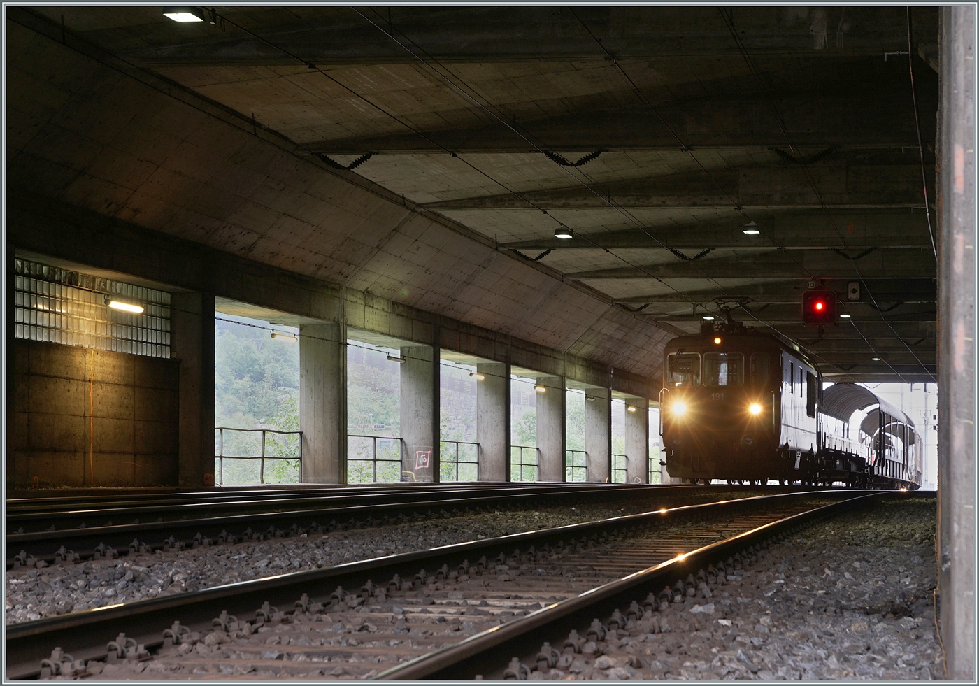 Ein von den Lichtverhältnissen etwas gewagtes Bild: die BLS Re 4/4 191 wartet in Goppenstein  mit ihrem (recht kurzen) Autotunnelzug (AT1) in einer Überbauung auf die Abfahrt nach Kandersteg. Die  Überbauung  nennt sich  Meigenbachtunnel  und ist 114 Meter lang.

12. Sept. 2024