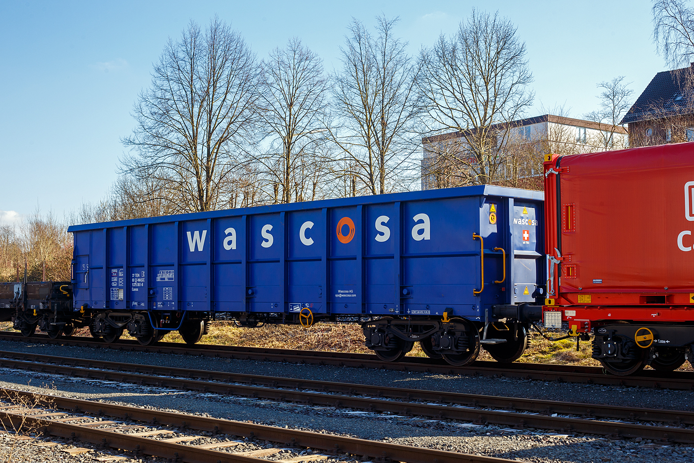 Ein recht neuer vierachsiger offener 82,5m³ Drehgestell-Güterwagen (Hochbordwagen) der Gattung Eanos, 37 80 5375 061-8 D-WASCO, der Wascosa AG, Luzern (CH), am 17 Februar 2025 abgestellt, im Zugverband eines Übergabegüterzuges, in Herdorf auf dem KSW Rbf Herdorf (Betriebsstätte Freien Grunder Eisenbahn - NE 447).

Der Wagen wurde 2023 von Astra Rail Industries (ARI) in Arad (Rumänien), seit 2016 Werk der Greenbrier Europe, gebaut.

Der Wagen ist für den Transport von Eisenschrott, Kohle sowie diversen Schüttgütern. Es ist ein robuster Wagen, da die Wände und der Boden in verstärkter Stahlkonstruktion, aus unlegiertem Baustahl S355J2+N, gefertigt sind. Die Blechdicken betragen 4 mm bei Seitenwand, 6 mm bei Stirnwand und 8 mm beim Boden. Die Wagen haben eine verstärkte Zugeinrichtung und ist für automatische Kupplungen (DAK) vorbereitet. 

Auffällig bei diesen Wagen ist, das sie keine große 2-flügelige Tür besitzen, sondern nur eine kleine Tür 750 x 930 mm je Wagenseite besitzen (hier links im Bild). 

TECHNISCHE DATEN:
Spurweite: 1.435 mm (Normalspur)
Achsanzahl: 4 in zwei Drehgestellen
Länge über Puffer: 15.740 mm
Drehzapfenabstand: 10.700 mm
Achsabstand im Drehgestell: 1.800 mm
Laufraddurchmesser: 920 mm (neu)
Drehgestelle: Y25 Lsd-KP1 (V)
Puffer: Gruppe A, Hub 105 mm
Länge x Breite der Beladeöffnung: 14.492 x 2.720 mm
Ladelänge: 14.490 mm
Ladefläche: 39,4 m²
Laderaum:  82,5 m³
Höchstgeschwindigkeit: 100 km/h (beladen) / 120 km/h (leer)
Max. Ladegewicht: 59,0 t ab Streckenklasse C, 67,0 t ab Streckenklasse D
Eigengewicht: 23.000 kg
Kleinster bef. Gleisbogenradius: R 35 m (im Wagenverbund150 m)
Bremse: KE-GR-A (K)
Bremssohle: Jurid C 810
Handbremse: Ja
Intern. Verwendungsfähigkeit: TEN-GE
