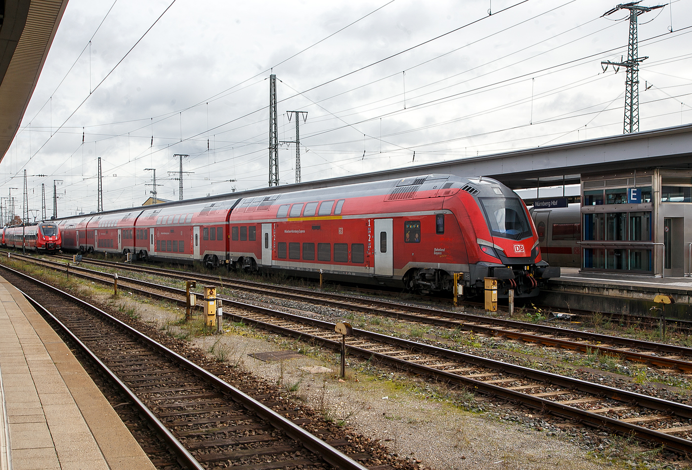 Eine Škoda Wendezug-Garnitur (Škoda Push-Pull) des München-Nürnberg-Express (mit 190 km/h zugelassen der schnellste RE in Deutschland) der DB Regio Bayern steht am 22.11.2022 im Hauptbahnhof Nürnberg. Leider verdecken die „Hamster“ die Lok.

Vorne der Škoda 1./2. Klasse klimatisierte Doppelstock-Reisezug-Steuerwagen, D-DB 70 80 86-94 005-1 der Gattung DABpbzf 770.0. 

Der Steuerwagen wurde von Škoda Vagonka Ostrava (deutsch Ostrau) im Osten von Tschechien 2016 gebaut, die Abnahme durch die DB erfolgte erst im September  2021. Škoda Vagonka Ostrava hat den Waggonhersteller Vagonka Studénka (früher Vagonka Tatra) übernommen. Die Produktion wurde 2001 nach Ostrava verlagert, wo modernisierte Fabrikhallen zur Verfügung standen.

TECHNISCHE DATEN vom Steuerwagen:
Spurweite: 1.435 mm
Länge über Kupplung: 26.950 mm
Drehzapfenabstand: 19.500 mm
Achsabstand im Drehgestell: 2.500 mm
Breite: 2.800 mm
Höhe über SOK: 4.630 mm
Einstiegshöhe über SOK: 760 mm
Leergewicht: 61 t
Höchstgeschwindigkeit: 190 km/h
Kleinster befahrbarer Gleisbogen: R 150 m
Sitzplätze: 17 in der 1 Klasse und 75 in der 2. Klasse
Bremse: KE-PR-A-Mg-mZ (D) mit ep und NBÜ

Auf einer Streckenlänge von 171 gibt es nur 8 bis 9 Halte, die Taktfolge ist alle 60 Minuten zwischen München und Ingolstadt (81 km) und alle 120 Minuten weiter von Ingolstadt nach Nürnberg (90 km).

München-Nürnberg-Express, abgekürzt MNX, MNE oder MüNüX, auch NIM-Express (benannt nach dem in ganzer Länge befahrenen Aus- und Neubaustreckenprojekt Nürnberg–Ingolstadt–München, ist mit 190 km/h zugelassen der schnellste Regional-Express-Linie in Deutschland (wird aber Ende 2022 von der neuen Linie Wendlingen-Ulm abgelöst). Auf einer Streckenlänge von 171 gibt es nur 8 bis 9 Halte, die Taktfolge ist alle 60 Minuten zwischen München und Ingolstadt (81 km) und alle 120 Minuten weiter von Ingolstadt nach Nürnberg (90 km). Seit dem Fahrplanwechsel im Dezember 2020 verkehren die Züge als RE 1

Da sich die sich die Zulassung der Škoda Wendezüge hatte wurden bis 2021 noch weiterhin, der seit 2006 eingesetzten, mit IC-Zügen gefahren. Die Verbindung München – Nürnberg ist bei Reisenden im Bahnland-Bayern sehr beliebt. Denn dank der Ausbaustrecke München – Ingolstadt und weiter über die Schnellfahrstrecke bis Nürnberg kann man im Regionalverkehr mit bis zu 190 km/h in gut eineinhalb Stunden zwischen der Landeshauptstadt und der Frankenmetropole reisen, und das Ganze mit dem Bayern-Ticket oder anderen Regionaltickets.

Entsprechend beliebt ist die Verbindung bei Reisenden im Bahnland Bayern – weshalb die Bayerische Eisenbahngesellschaft, die den Schienenpersonennahverkehr plant, finanziert und kontrolliert, mit neuen Zuggarnituren das Angebot deutlich ausweiten möchte. Neue Doppelstockzüge von Skoda sollen künftig für mehr Verbindungen und mehr Platz in den Zügen sorgen. Die bis dahin eingesetzt en 101er bespannten Wendezug-Garnituren aus dem InterCity-Verkehr verbleiben zunächst als Reserve bei der Deutschen Bahn.

Rückblick: Im Juni 2013 hatte die Bayerische Eisenbahngesellschaft (BEG) den Zuschlag für den Regionalverkehr auf der Bahnstrecke München – Ingolstadt – Nürnberg an DB Regio Bayern erteilt. Für den Verkehr über die Neubaustrecke schloss die Deutsche Bahn mit der Firma Škoda einen Vertrag über die Lieferung von 42 Fahrzeugen (sechs Garnituren aus je sechs Reisezugwagen und je einer Lok) ab. Vertraglich vereinbart war eigentlich ein Start mit Beginn des Verkehrsvertrages im Dezember 2016.  