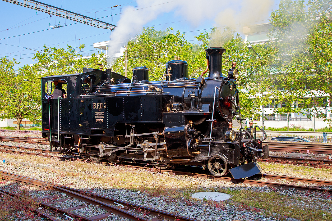 Es raucht und dampft in Vevey...
Die Dampflokomotive für gemischten Adhäsions- und Zahnradbetrieb BFD 3 HG 3/4 (Brig–Furka–Disentis-Bahn), später FO 3 (Furka-Oberalp-Bahn), heute im Bestand der Museumsbahn Blonay–Chamby, rangiert am 28.05.2023 in Vevey. Am Pfingstwochenende fand bei der das Schweizer Dampffestival 2023 / Festival suisse de la Vapeur 2023 statt.

Die Lok Nr. 3 wurde 1969 der Museumsbahn Blonay–Chamby (BC) geschenkt, während Nr. 4 als Reserve weiterhin bei der Furka-Oberalp-Bahn (FO) blieb und hauptsächlich für Nostalgiefahrten verwendet wurde. Mit Ablauf der Untersuchungsfristen wurde sie (FO 4) 1972 abgestellt. Nach einigen Stationen ging die Lok 4 im Jahr 1997 zunächst leihweise an die Dampfbahn Furka-Bergstrecke über. Anschließend wurde sie in der DFB-Werkstätte betriebsfähig aufgearbeitet und 2006 in Betrieb genommen. Die Lok wurde historisch korrekt restauriert und vollständig schwarz lackiert. Anlässlich der Eröffnung des Streckenabschnitts Gletsch–Oberwald im Jahr 2010 ging die Lok als Geschenk an die DFB über.

Auch die ehemaligen FO Loks 1 und 9, sowie Überresten der Loks 2 und 8, sind heute bei der Dampfbahn-Furka-Bergstrecke. Unter der Bezeichnung „Back to Switzerland“ kehrten die vier HG 3/4 aus Vietnam 1990 Jahre in die Schweiz zurück.

Die HG 3/4 Dampflokomotiven haben vier Zylinder, zwei außenliegende für den Adhäsionsantrieb und zwei innenliegende für den Zahnradantrieb. 

TECHNISCHE DATEN:
Länge über Puffer: 8.754 mm
Dienstgewicht: 42 t
Triebraddurchmesser: 910 mm
Laufraddurchmesser: 600 mm
Zahnrad Teilkreis: 688 mm
Zahnrad Zähne/Teilung: 18 Zähne / 120 mm (Abt 2-lamellig)
Anhängelast 110 ‰ Steigung: 60 t
Max. Geschwindigkeit Adhäsion: 45 km /h
Max. Geschwindigkeit Zahnrad: 20 km/h
Leistung: 600 PS (440 kW)
Antriebssystem: Getrennte Adhäsions- & Zahnradmaschine nach System Abt als Heissdampf Vierzylinderverbundmaschine
Bremsen: Vakuumbremse, Riggenbach'sche Gegendruckbremse
Steuerung Adhäsion: Walscherts Kolbenschieber
Steuerung Zahnrad: Joy Kolbenschieber
Zylinderdurchmesser Adhäsion: 420 mm
Zylinderdurchmesser Zahnrad: 560 mm
Kesseldruck: 14 bar
Rostfläche / Heizfläche:1,3 m² / 63 m²
Siede- / Rauchrohre: 95 / 15 Rohre
Kesselwasser-Inhalt: 2,6 m³
Wasservorrat: 3,15 m³
Kohlenvorrat: ca. 1,3 t
