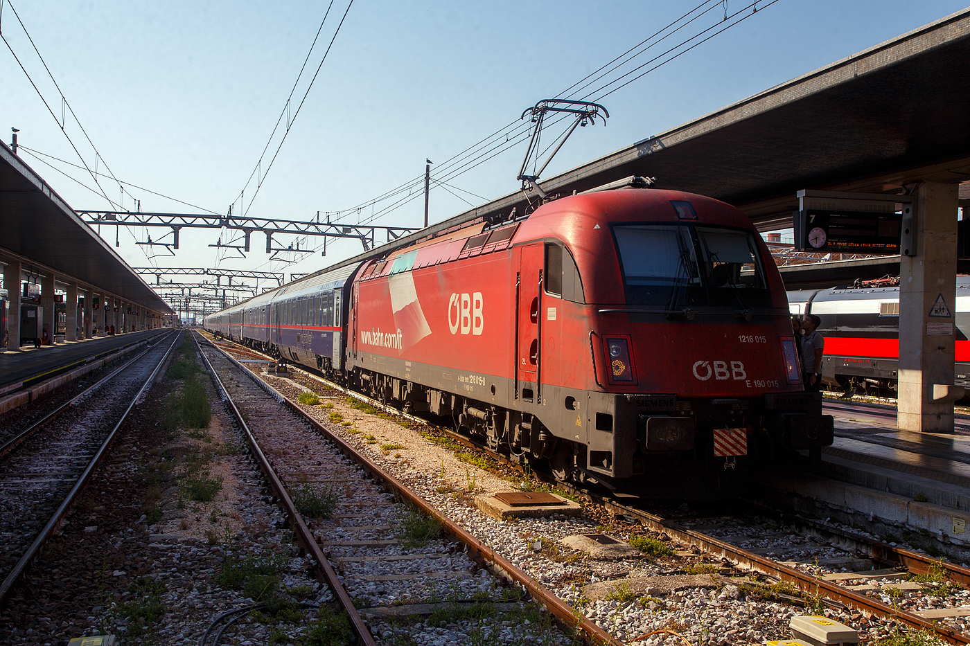 Im Sandwich, zweier ÖBB Taurus III der Reihe 1216 (hier am Zugschuss die 1216 016 / E 190 015 (A-ÖBB 91 81 1216 015-8), der ÖBB Nightjet EN 236 / 40236 von Venezia SL über Udine, Villach und Salzburg nach München steht am Abend des 24 Juli 2022 im Bahnhof Venedig Santa Lucia (italienisch Stazione di Venezia Santa Lucia) zur Abfahrt bereit, mit dem wir gleich mitfahren. Die Siemens ES 64 U4-A (Variante A) besitzen die Zulassung für Österreich, Deutschland, Italien und Slowenien.

Eigentlich sollte/geht der Zuglauf von Venedig über Udine und dann von dort über die Pontafelbahn/Ferrovia Pontebbana nach Villach Wocheiner Bahn gehen, aber diese Strecke war gesperrt. Aber auch der Brenner und die Wocheiner Bahn von Trieste über Jesenice nach Villach war gesperrt.

So ging unsere Fahrt über Villa Opicina, über ehem. Österreichische Südbahn bis zur slowenischen Hauptstadt Ljubljana (Laibach) und von dort (über die ehem. Kronprinz-Rudolf-Bahn) über Jesenice (Aßling) nach Villach Hbf. Von Villach ging es dann wieder planmäßig über Salzburg nach München Hbf, wo wir dann mit über 2 Stunden Verspätung eintrafen. Aber die längere Fahrt von Ljubljana haben wir nicht bemerkt, da wir in der Nacht geschlafen haben.
