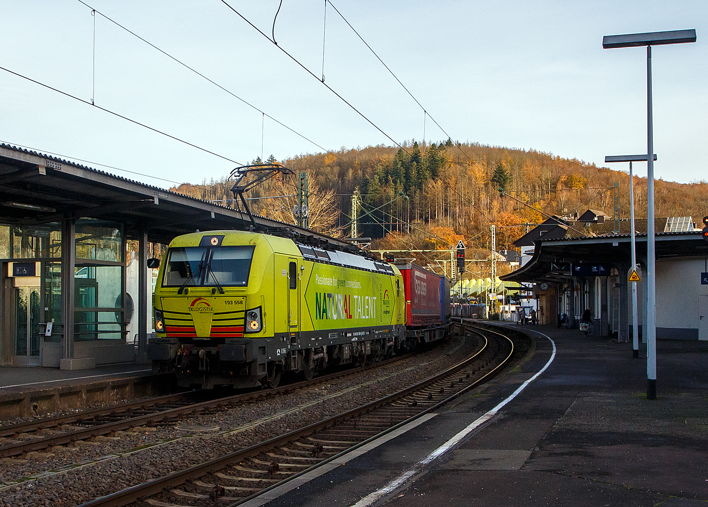 Nach langer Enthaltsamkeit konnte ich am 22 November 2023 endlich mal wieder Güterzüge auf den Siegstrecke ablichten, hier fährt die an die TX Logistik AG (Troisdorf) vermietete Siemens Vectron MS 193 558 „Natural Talent“ (91 80 6193 558-4 D-ATLU) der Alpha Trains Luxembourg s.à.r.l. (Luxembourg) mit einem KLV-Zug durch Betzdorf (Sieg) in Richtung Köln.

Die Vectron Lokomotive ist als MS – Lokomotive (Mehrsystemlok) mit 6.400 kW konzipiert und zugelassen für Deutschland, Österreich und Italien.

Die TX Logistik AG (TXL) ist ein im Jahr 1999 in Bad Honnef gegründetes Eisenbahnverkehrsunternehmen mit heutigem Sitz in Troisdorf, das heute zur Mercitalia Group gehört, die wiederum ein 100 prozentiges Tochterunternehmen der italienischen Staatsbahn Ferrovie dello Stato Italiane FS ist. Mittlerweile gehört das Unternehmen mit zu den Größten für den Schienengüterverkehr in Europa.

Das Unternehmen bietet den ganzen Umfang an Schienengüterverkehr, inklusive Containertransport und kombiniertem Verkehr an. Wichtigste Transportstrecken sind von den Häfen Hamburg, Bremerhaven, Rotterdam und Antwerpen nach Süddeutschland, Schweiz, Österreich und Italien.