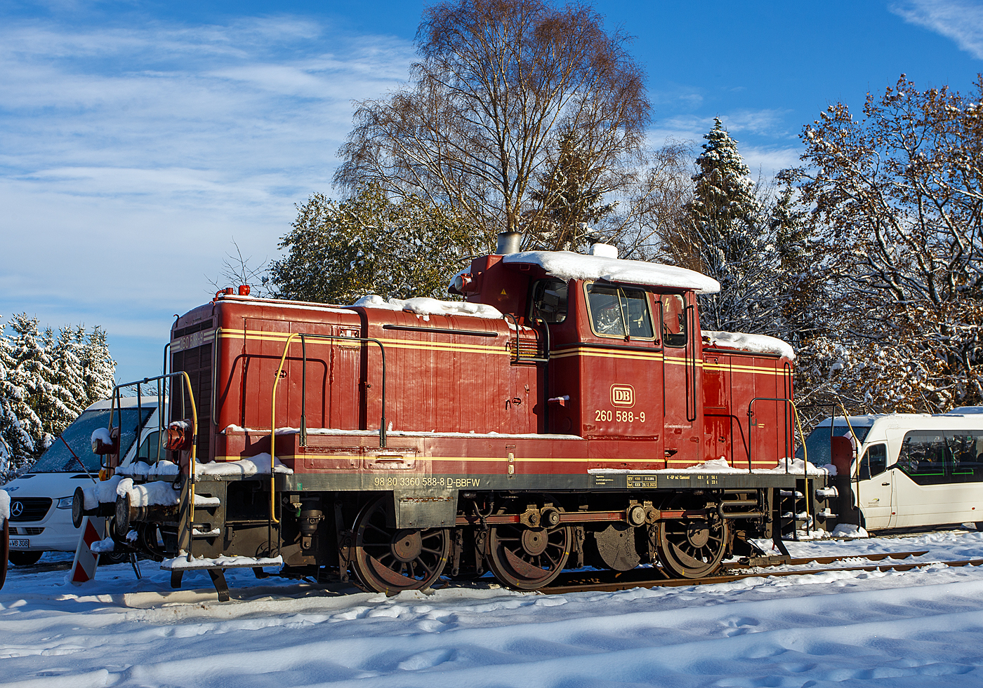 Nicht nur im Süden der Republik hat es etwas geschneit, wie hier auf dem Westerwald auf der Bindweide, aber nicht so mächtig. 
Die 260 588-9 alias 360 588-8 (98 80 3360 588-8 D-BBFW) vom Bergische Bahnen Förderverein Wupperschiene e. V. ist am 03 Dezember 2023 (am 1. Advent) auf dem Betriebshof der Westerwaldbahn (WEBA) auf der Bindweide bei Steinebach/Sieg abgestellt.

Die V60 der leichten Ausführung wurde 1960 von Krupp unter der Fabriknummer 4011 gebaut und als V 60 588 an die Deutsche Bundesbahn geliefert. Nach der Umzeichnung 1968 in 260 588-9 und 1987 in 360 588-8 wurde die V60 im Jahr 2002 bei der DB ausgemustert und ging an die EfW-Verkehrsgesellschaft mbH in Frechen, bis sie 2013 zum Bergische Bahnen Förderverein Wupperschiene e. V. kam.

Die V60-Familie:
Die Deutsche Bundesbahn hatte nach ihrer Gründung einen Mangel an kleinen Rangierlokomotiven. Daher wurde ab 1951 eine Dieselrangierlok entwickelt, an deren Bau und Entwicklung fast alle namhaften Lokomotivfabriken beteiligt waren. Die neue Baureihe wurde zunächst als V 60 bezeichnet. Noch 1955 wurden die ersten 275 Serienloks in Auftrag gegeben, sie hatten den Motor GTO 6 von Maybach und das Dreiganggetriebe L 37 zUB von Voith.

Durch einen verstärkten Rahmen erhielten einige der Lokomotiven ein höheres Reibungsgewicht von 53 Tonnen (somit schwere Ausführung, spätere BR 261/361) statt 48,3–49,5 Tonnen. Zusätzlich konnten bei diesen Loks für den schweren Dienst noch bis zu sechs Tonnen Ballast mitgeführt werden, die Baureihenbezeichnung blieb jedoch bei V 60. Insgesamt wurden 942 Lokomotiven der leichten und schweren Ausführung zusammen genommen geliefert. Anhand der Ordnungsnummer war eine Unterscheidung der leichten und der schweren Ausführung nicht möglich, erst zum 1. Januar 1968 wurde mit der Einführung der computerlesbaren Nummern für die DB-Lokomotiven die Baureihe V 60 in die 618 Fahrzeuge umfassende Baureihe 260 (leichte Ausführung) und 322 Fahrzeuge umfassende Baureihe 261 (schwere Ausführung) aufgeteilt. Bei den vierstelligen Ordnungsnummern entfiel die führende Tausenderstelle.

Die V60 wurden 1987 als Kleinloks eingestuft und trug seitdem die Baureihenbezeichnung 360 (leichte Ausf.) bzw. 361 (schwere Ausf.). Die Einstufung als Kleinlok sparte Personalkosten, da die Bundesbahn nun keine „Lokführer“ mehr einsetzen musste, sondern „Kleinlokbediener“, deren Ausbildung günstiger war. Durch die Umstellung der Führerschein-Systematik hat die Einstufung als Kleinlok heute nur noch deklaratorische Bedeutung, die V 60 würde nach wie vor die technischen Anforderungen an „großen“ Lokomotiven gemäß EBO erfüllen. Der Einbau von Funkfernsteuerungen erlaubte Einmann-Rangierfahrten, die fernsteuerbaren Modelle wurden Baureihe 364 (leichte Bauart) bzw. 365 (schwere Bauart).
