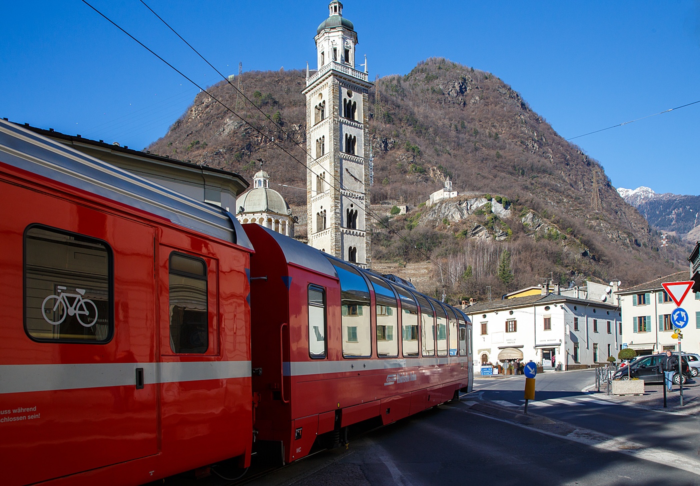 RhB Bp 2505 ein vierachsiger zweite Klasse Stadler Bernina-Panoramawagen, eingereiht in einen RhB Regio von St. Moritz nach Tirano, am 19 Februar 2017 auf der Via Elvezia in Tirano. Links die Basilika Madonna di Tirano, oben die Chiesa di Santa Perpetua und geradeaus an der Ecke das Caff� Basilika wo auch der Caff� espresso ein Genuss ist.

F�r den ber�hmten Bernina-Express lie� die Rh�tische Bahn RhB 26 Panorama-Wagen in zwei Serien (2000 und 2006/7) bauen. Gegen�ber den zuvor f�r andere Strecken gebauten Wagen, weisen die Bernina-Wagen eine um 3,2 m geringere Gesamtl�nge auf. Es entstanden neun 1.-Klasse- und 17 2.-Klasse-Wagen, die sich gro�er Beliebtheit bei den Fahrg�sten erfreuen. 

Dieser Wagen ist aus der 1. Serie  wurde 2000 von Stadler gebaut. Die Wagen der 1. Serie besitzen noch Drehgestelle vom Typ SIG 90, die aber auch von Stadler gebaut wurden. Die Wagen der 2. Serie besitzen dagegen Drehgestell mit Luftfederung und vakuumgesteuerter Druckluftbremse.

TECHNISCHE DATEN:
Hersteller: Stadler Rail
Baujahr: 2000
Spurweite: 1.000 mm
Anzahl der Achsen: 4 (2´2´)
L�nge �ber Puffer: 16.460 mm
Drehgestellbauart: SIG 90
Sitzpl�tze: 50
Stehpl�tze: 42
Eigengewicht: 19,3  t
zul�ssige Geschwindigkeit: 100 km/h
Lauff�hig: StN (Stammnetz) / BB (Berniabahn) / MGB (Matterhorn Gotthard Bahn)
Besonderheiten: Klimaanlage