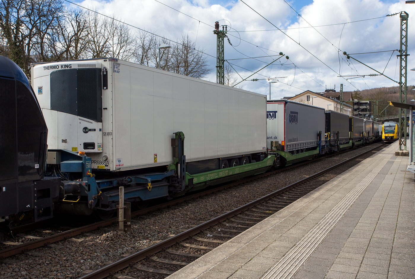 Spezieller sechsachsiger Gelenk-Taschenwagen System HELROM, 87 80 4993 017-4 D-HELR, der Gattung Sdmrs, der HELROM Trailer Rail am 28 März 2024 im Zugverband bei der Durchfahrt im Bahnhof Kirchen (Sieg).

Der Clou bei HELROM sind neuartige Transportwaggons, die keine teuren Kran- oder Verladeeinrichtungen brauchen. Auch müssen die Sattelauflieger nicht kranmanipulierbar sein, das sind auch hier zu Lande die wenigsten. Dieses Megaswing-System ist ein spezieller Taschenwagen mit schwenkbaren Aufnahmewannen für Sattelauflieger. Hydraulikstützen dienen als Stabilisierung, wenn die Wanne nach links oder rechts ausschwenkt. Die Beladung der Wanne mit einem Sattelauflieger erfolgt rückwärts. Nach Absatteln des Sattelaufliegers wird die Wanne angehoben und schwenkt wieder ein. Der Sattelauflieger wird leicht abgesenkt und mit dem Waggon fest verbunden, er ist nun auf dem Waggon sicher verstaut. Die Technik ist im Waggon verbaut.

TECHNISCHE DATEN:
Hersteller: Gök Yapi (Türkei)
Spurweite: 1.435 mm
Länge über Puffer: 34.230 mm
Drehzapfenabstand: 2 x 14.200 mm
Achsabstand im Drehgestellen: 1.800 mm
Laufraddurchmesser: 920 mm (neu)
Eigengewicht: 45.200 kg
Max. Zuladung bei Lastgrenze: 76,0 t (ab Streckenklasse D)
Max. Geschwindigkeit: 100 km/h (beladen) / 120 km/h (leer)
Kleinster befahrbarer Gleisbogen: R 75 m
Bremse: 2 x MH-GP-A (K)
Bremssohle: Cosid 810
Feststellbremse: Ja (aufs mittlere Drehgestell)
Intern. Verwendungsfähigkeit: TEN CW
