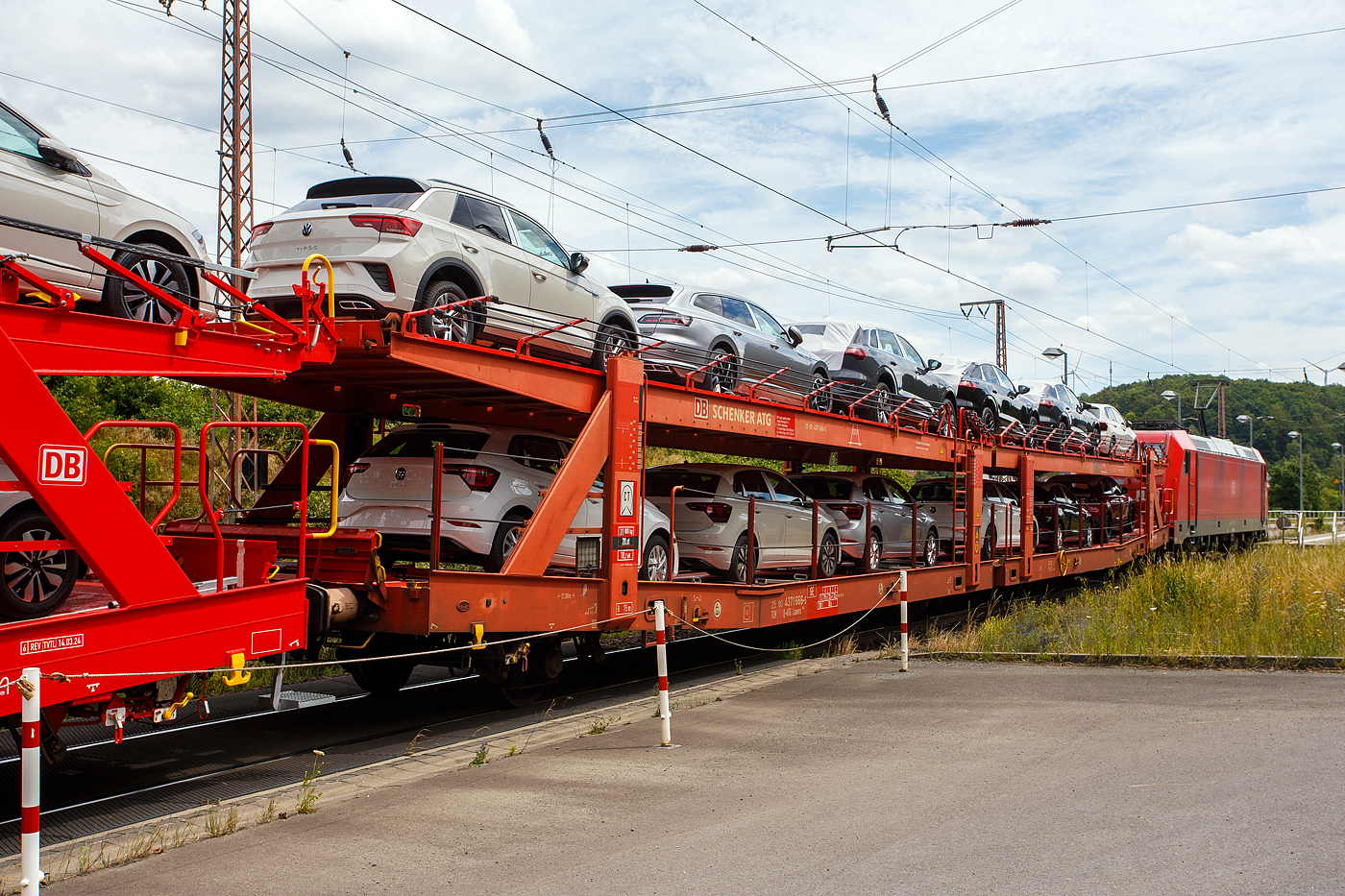Vierachsiger (2 x zweiachsiger) Doppelstock-Autotransportwagen, 25 80 4371 666-5  D-ATG, der Gattung Laaers 560, der DB Cargo Logistics GmbH (ex DB Schenker ATG), am 19 Juli  2024 im Zugverband, direkt hinter der DB Cargo 185 230-0 (91 80 6185 230-0 D-DB), bei der Zugdurchfahrt in Rudersdorf (Kreis Siegen), hier beladen mit VW PKW´s aus der „Stadt des KdF-Wagens bei Fallersleben“ (ab 1945 Wolfsburg).

Diese Waggons haben zwei Ladeebenen und sind für den europaweiten Transport geeignet. Sie werden für den internationalen Transport von PKWs, SUVs und Vans eingesetzt und bieten maximale Flexibilität durch eine stufenlos verstellbare obere Ladeebene. Aufgrund der hohen Lastgrenze (bis 33 t) ist der Transport von besonders schweren Fahrzeugen der genannten Typen möglich.

Damit sowohl ein typenreiner Transport als auch eine Mischverladung in den unterschiedlichen Lademaßen möglich ist, kann die obere Ladeebene hinsichtlich der Transportstellungen stufenlos eingestellt werden.

Durch die Entwicklung eines veränderten Ladungssicherungssystems wurde den Kundenanforderungen nach optimierten Transportmöglichkeiten für Fahrzeuge mit niedrigerer Bodenfreiheit Rechnung getragen.

TECHNISCHE DATEN:
Gattung: Laaers (Bauart 560)
Erstes Baujahr der Wagengattung: 2007
Spurweite: 1.435 mm
Anzahl der Achsen: 4 (2 x 2)
Länge über Puffer : 31.000 mm
Achsabstände: 10.000 mm / 5.160 mm / 10.000 mm
Laufraddurchmesser (neu): äußere 840 mm und mittlere 730 mm
Ladelänge : 30.070 mm (unten) / 30.550 mm (oben)
Ladelänge waagerechter Teil untere Ebene: 19.400 mm
Ladebreite : 2.950 (unten) / 2.750 mm (oben)
Höchstgeschwindigkeit: 100 km/h (120 km/h leer)
Eigengewicht: 31.000 kg
Max. Zuladung bei Lastgrenze S: 33,0 t (ab Streckenklasse B, bei A 29,0 t)
Max. Zuladung der Ladeebenen: unten und oben jeweils max. 18 t
Max. Gewicht je Pkw: 2.800 kg (Radlast max. 1 t)
Anzahl der Radvorleger: 64
Höhe Geländer oben: 600 mm
Kleinster befahrb. Gleisbogenhalbmesser: 75 m
Bremse: KE-GP-A (K)
Bremssohle: Jurid 816 M
Handbremse: Ja
Intern. Verwendungsfähigkeit: TEN-GE
