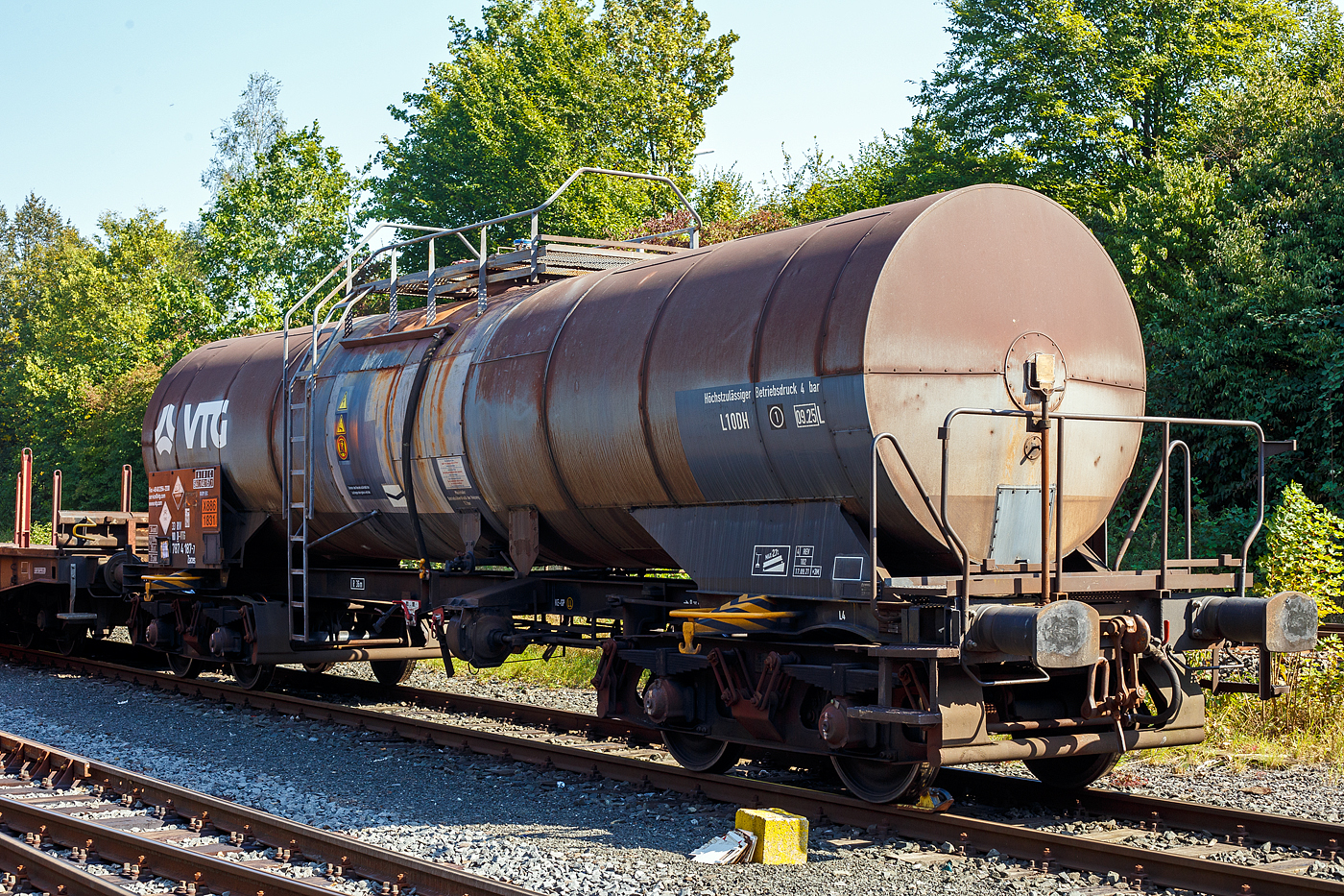 Vierachsiger 34 m³ Drehgestell-Kesselwagen mit Bremserbühne, 33 80 7874 187-7 D-VTG, der Gattung Zaces, der VTG Rail Europe GmbH (Hamburg), abgestellt am 18 September 2024 in Herdorf, im Zugverband eines Übergabezuges der KSW, auf dem Rbf. der KSW.

Die Gefahrguttafel (X886/1831) zeigt an, was drin war oder ist:
Schwefelsäure (rauchend), auch bekannt als Oleum oder Vitriol (rauchend). Sie wird unteranderem zur Herstellung von Sprengstoffen verwendet, was hier bei der Fa. Dynamit Nobel Defence in Burbach-Würgendorf der Fall ist.

TECHNISCHE DATEN:
Gattung: Zaces
Spurweite: 1.435 mm (Normalspur)
Länge über Puffer : 14.400 mm
Drehzapfenabstand: 9.360 mm
Achsabstand im Drehgestell: 1.800 mm
Laufraddurchmesser: 920 mm (neu)
Höchstgeschwindigkeit: 100 km/h
Eigengewicht: 22.280 kg
Max. Ladegewicht: 57,7 t (ab Streckenklasse C)
Gesamtvolumen: 34.000 Liter (34 m³)
Bauart der Bremse: KE-GP (LL)
Bremssohle: IB 116
Handbremse: Ja (von Bremserbühne  bedienbar)
Kleinster befahrbarer Gleisbogen: R 36 m
Tankcode: L10DH (Zulässiger Betriebsüberdruck 4 bar)
Behälterwerkstoff : Edelstahl
Intern. Verwendungsfähigkeit: RIV

Die Bedeutung der Gattung Zaces:
Z = Kesselwagen
a = 4 Radsätze
c = Entladung durch Druckluft oder Luftstöße
e = mit Heizung
s = zugelassen für Züge bis 100 km/h (beladen)