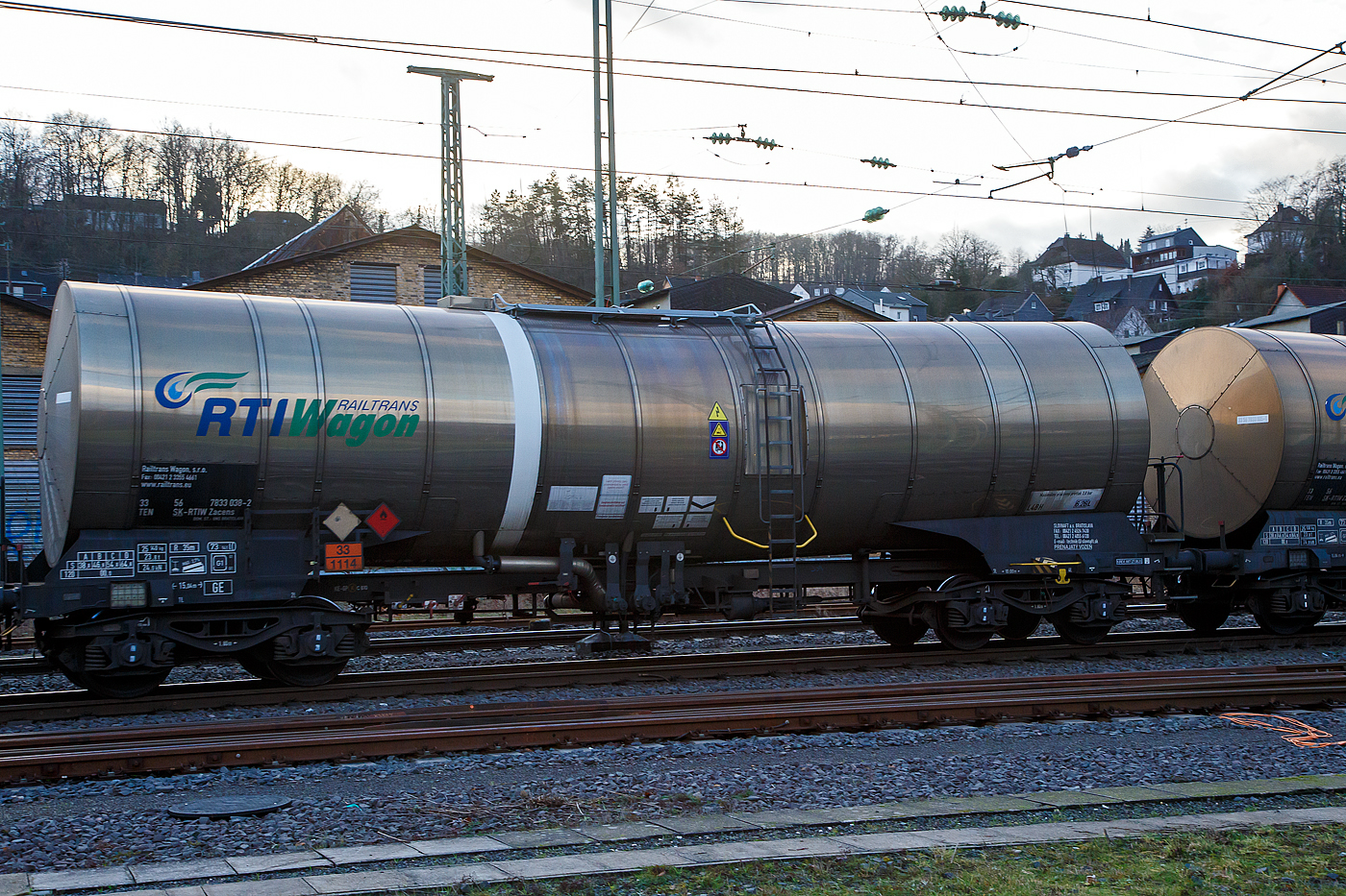 Vierachsiger 73 m³ Drehgestell-Kesselwagen, 33 56 7933 038-2 SK-RTIW, der Gattung Zacens, der RTI Railtrans Wagon s.r.o. am 11.01.2023 im Zugverband bei einer Zugdurchfahrt in Betzdorf (Sieg).

Das Ladegut (laut Gefahrgutnummer 33/1114) ist hier Benzol, eine flüssige organische Verbindung mit einem charakteristischen aromatischen Geruch. Die Verbindung ist ein aromatischer Kohlenwasserstoff und mischbar mit fast allen organischen Solventien, jedoch kaum mit Wasser. Benzol wird zur Herstellung wichtiger Industriechemikalien wie zum Beispiel Cyclohexan, Ethylbenzol und Nitrobenzol verwendet. Im Motorenbenzin sind in Deutschland und der EU nach EN 228 nur noch maximal ein Prozent erlaubt. Als Lösungsmittel wird Benzol nicht mehr verwendet, da es krebserregend ist.

Die Bedeutung der Gattungs- und Kennbuchstaben (hier Zacens):
Z - Kesselwagen für den Transport von flüssigen oder gasförmigen Erzeugnissen
a - mit vier Radsätzen
c - mit Entladung unter Druck
e - mit Heizeinrichtung
n - mit vier Radsätzen höchste Lastgrenze über 60 t
s - Höchstgeschwindigkeit 100 km/h (beladen)

TECHNISCHE DATEN:
Gattung: Zacens 
Spurweite: 1.435 mm
Länge über Puffer : 15.040 mm
Drehzapfenabstand: 10.000 mm
Achsabstand im Drehgestell: 1.800 mm
Laufraddurchmesser: 920 mm (neu)
Drehgestelltyp: Y25 Ls1-K (BA 314)
Höchstgeschwindigkeit: 100 km/h / 120 km/h (leer)
Eigengewicht: 25.140 kg
Nutzlast: 54,8 t ab Streckenklasse C / 64,8 ab Streckenklasse D
Gesamtvolumen: 73.141 Liter (73 m³)
Max. Betriebsdruck: 3,0 bar
Tankcode: L 4 BH
L= Tank für Stoffe in flüssigem Zustand (flüssige Stoffe oder feste Stoffe, die in geschmolzenem Zustand zur Beförderung aufgegeben werden)
4= zutreffender Mindestprüfdruck in bar
B = Tank mit Bodenöffnungen mit 3 Verschlüssen für das Befüllen oder Entleeren 
H = luftdicht verschlossener Tank
Bremse: KE-GP-A (K)
Bremssohle: C810
Intern. Verwendungsfähigkeit: TEN-GE