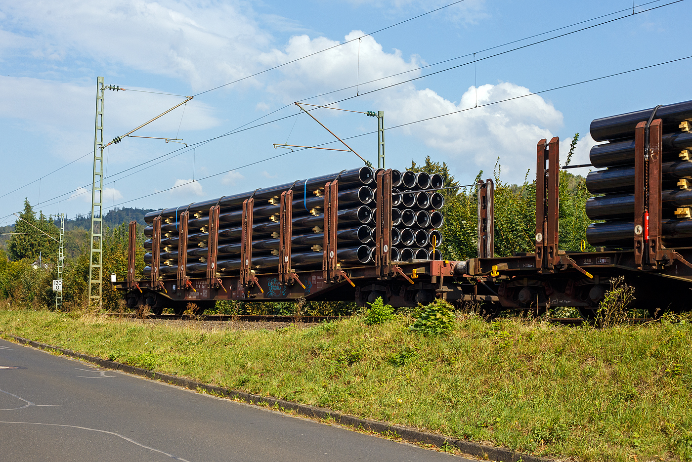 Vierachsiger Drehgestell-Flachwagen mit 8 Doppelrungenpaaren mit integrierter Niederbindeeinrichtung, 31 80 4723 857-7 D-DB, der Gattung Snps 719.1, der DB Cargo AG, am 19 September 2024 im Zugverband bei einer Zugdurchfahrt im Bahnhof Kirchen (Sieg). Hier beladen mit HFI-längsnahtgeschweißte Stahlrohre Ø 323.9 (DN/NW 300 mm bzw. 12 ¾ Inch) in Herstellungslänge vom 12 m. Der Hersteller der Stahlrohre ist die Salzgitter Mannesmann Line Pipe GmbH in Siegen (ex RW Fuchs).

Der Drehgestell-Flachwagen wurde speziell für den Transport von Rohren, Profilstahl, Flachstahlprodukten sowie Stamm- und Schnittholz entwickelt und zeichnet sich durch hohe Ladekapazität aus. Das Ladegut wird durch Rungen mit Schichtholzleisten und Kunststoffspitzen geschont (nur bei BA 719.1 Stahlhalbzeuge. Wird bei der BA 719.0 Timber (Holz) nicht benötigt und ist daher auch nicht montiert.). Die Längsseiten sind jeweils mit acht besonders breiten und belastbaren Rungen ausgerüstet, die mit dem Untergestell fest verbunden sind. Zur Verzurrung des Ladegutes ist jedes Rungenpaar mit einer Niederbindeeinrichtung versehen, die von einer Person bedient werden kann. Die Wagen wurden ab 1980 als Sps 719 beschafft und ab 1988 in Snps 719 umgezeichnet.

Zur Aufnahme und Abstützung der Ladung sind auf dem Wagenboden Ladeschwellen und an den Wagenlängsseiten Rungen angebracht. Zur Verzurrung der Ladung sind von Hand zu bedienende Niederbindeeinrichtungen vorhanden. Für die Auflage des Ladegutes sind hölzerne Ladeschwellen im Rungenbereich und im Abstand von 1 m von Wagenende vorhanden. Außerdem sind feste 5 mm niedrigere Hilfsladeschwellen zwischen den Rungen zur Unterstützung von leicht durchhängendem Ladegut (z. B. Schnittholz) angeordnet. Die Ladeschwellen sind genügend hoch, so dass die handelsüblichen Umschlagmittel verwendet werden können. Der Wagenboden ist mit einem begehbaren Loch- bzw. Riffelblech vollständig abgedeckt. Zur Aufnahme von Lasten oder zum Befahren mit Flurförderfahrzeugen sind die Abdeckungen nicht geeignet. Zur Sicherung der Ladung sind auf jeder Wagenlängsseite in gleichmäßigen Abständen 8 Rungen vorhanden. Die Rungen sind mit dem Untergestell-Außenlangträger fest verbunden und so ausgeführt, dass sie die durch die Ladung entstehenden Kräfte in Wagenlängs- und Wagenquerrichtung sicher aufnehmen können. Die Innenseiten der Rungen sind ausgekleidet.

Zur Verzurrung des Ladegutes ist jedes Rungenpaar mit einer Niederbindeeinrichtung ausgerüstet, die von einer Person bedient werden kann. Die Spanngurte sind zur Schonung des Ladegutes mit einem elastischen Werkstoff ummantelt. Die Länge des Gurtes und die Teilung der Raster sind so gewählt, dass auch Ladungen, die nur etwa die halbe Rungenhöhe einnehmen, verzurrt werden können.

TECHNISCHE DATEN:
Gattung: Snps 719.1
Spurweite: 1.435 mm (Normalspur)
Länge über Puffer: 20.840 mm
Drehzapfenabstand: 15.800 mm
Radsatzstand in den Drehgestellen: 1.800 mm
Ladelänge: 19.000 mm
Ladebreite: 2.723 mm (zwischen den Rungen)
Fußbodenhöhe über SO: 1.280 mm (OK Ladeschwelle)
Rungenhöhe: 2.000 mm
Eigengewicht: 24.400 kg
Zuladung bei Lastgrenze S: 63 t (ab Streckenklasse D)
Max. Geschwindigkeit: 100 km/h / 120 km/h (leer)
Kleinster Gleisbogenhalbmesser: 35 m
Bauart der Bremse: KE-GP (LL)
Bremssohle: IP 116
Handbremse: Ja
Verwendungsfähigkeit: RIV