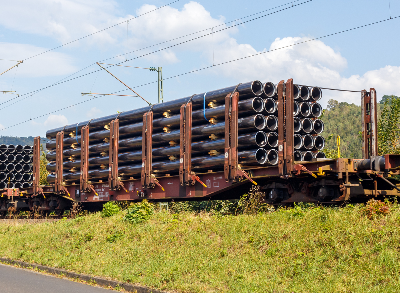 Vierachsiger Drehgestell-Flachwagen mit 8 Doppelrungenpaaren mit integrierter Niederbindeeinrichtung, 31 80 4724 039-1 D-DBSNI, der Gattung Snps 719.1, der DB Cargo Logistics GmbH (ex DB Schenker Nieten GmbH), am 19 September 2024 im Zugverband bei einer Zugdurchfahrt im Bahnhof Kirchen (Sieg). Hier beladen mit HFI-längsnahtgeschweißte Stahlrohre Ø 323.9 (DN/NW 300 mm bzw. 12 ¾ Inch) in Herstellungslänge vom 12 m. Der Hersteller der Stahlrohre ist die Salzgitter Mannesmann Line Pipe GmbH in Siegen (ex RW Fuchs).

Der Drehgestell-Flachwagen wurde speziell für den Transport von Rohren, Profilstahl, Flachstahlprodukten sowie Stamm- und Schnittholz entwickelt und zeichnet sich durch hohe Ladekapazität aus. Das Ladegut wird durch Rungen mit Schichtholzleisten und Kunststoffspitzen geschont (nur bei BA 719.1 Stahlhalbzeuge. Wird bei der BA 719.0 Timber (Holz) nicht benötigt und ist daher auch nicht montiert.). Die Längsseiten sind jeweils mit acht besonders breiten und belastbaren Rungen ausgerüstet, die mit dem Untergestell fest verbunden sind. Zur Verzurrung des Ladegutes ist jedes Rungenpaar mit einer Niederbindeeinrichtung versehen, die von einer Person bedient werden kann. Die Wagen wurden ab 1980 als Sps 719 beschafft und ab 1988 in Snps 719 umgezeichnet.

Zur Aufnahme und Abstützung der Ladung sind auf dem Wagenboden Ladeschwellen und an den Wagenlängsseiten Rungen angebracht. Zur Verzurrung der Ladung sind von Hand zu bedienende Niederbindeeinrichtungen vorhanden. Für die Auflage des Ladegutes sind hölzerne Ladeschwellen im Rungenbereich und im Abstand von 1 m von Wagenende vorhanden. Außerdem sind feste 5 mm niedrigere Hilfsladeschwellen zwischen den Rungen zur Unterstützung von leicht durchhängendem Ladegut (z. B. Schnittholz) angeordnet. Die Ladeschwellen sind genügend hoch, so dass die handelsüblichen Umschlagmittel verwendet werden können. Der Wagenboden ist mit einem begehbaren Loch- bzw. Riffelblech vollständig abgedeckt. Zur Aufnahme von Lasten oder zum Befahren mit Flurförderfahrzeugen sind die Abdeckungen nicht geeignet. Zur Sicherung der Ladung sind auf jeder Wagenlängsseite in gleichmäßigen Abständen 8 Rungen vorhanden. Die Rungen sind mit dem Untergestell-Außenlangträger fest verbunden und so ausgeführt, dass sie die durch die Ladung entstehenden Kräfte in Wagenlängs- und Wagenquerrichtung sicher aufnehmen können. Die Innenseiten der Rungen sind ausgekleidet.

Zur Verzurrung des Ladegutes ist jedes Rungenpaar mit einer Niederbindeeinrichtung ausgerüstet, die von einer Person bedient werden kann. Die Spanngurte sind zur Schonung des Ladegutes mit einem elastischen Werkstoff ummantelt. Die Länge des Gurtes und die Teilung der Raster sind so gewählt, dass auch Ladungen, die nur etwa die halbe Rungenhöhe einnehmen, verzurrt werden können.

TECHNISCHE DATEN:
Gattung: Snps 719.1
Spurweite: 1.435 mm (Normalspur)
Länge über Puffer: 20.840 mm
Drehzapfenabstand: 15.800 mm
Radsatzstand in den Drehgestellen: 1.800 mm
Ladelänge: 19.000 mm
Ladebreite: 2.723 mm (zwischen den Rungen)
Fußbodenhöhe über SO: 1.280 mm (OK Ladeschwelle)
Rungenhöhe: 2.000 mm
Eigengewicht: 24.400 kg
Zuladung bei Lastgrenze S: 63 t (ab Streckenklasse D)
Max. Geschwindigkeit: 100 km/h / 120 km/h (leer)
Kleinster Gleisbogenhalbmesser: 35 m
Bauart der Bremse: KE-GP (LL)
Bremssohle: IP 116
Handbremse: Ja
Verwendungsfähigkeit: RIV