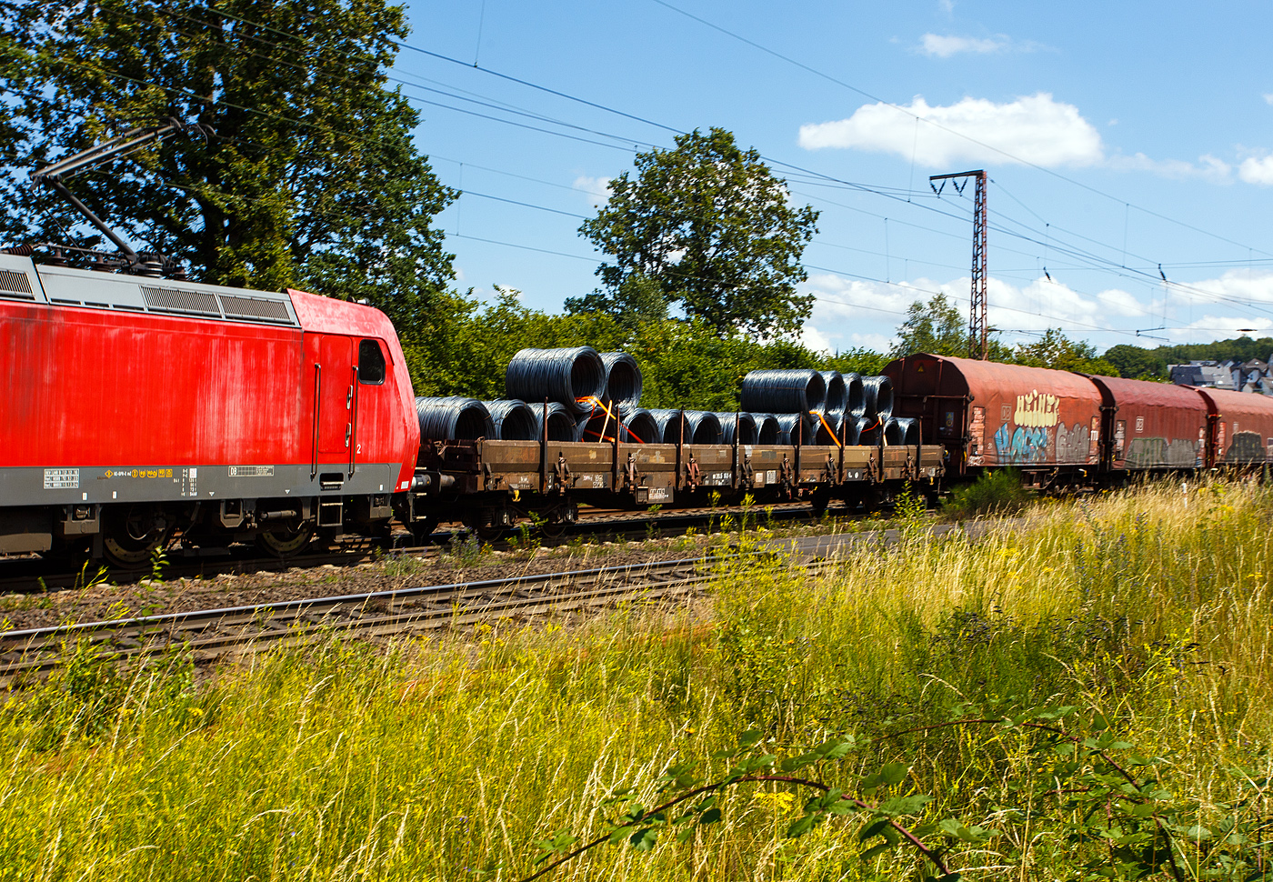 Vierachsiger Drehgestell-Flachwagen, mit Seiten-, Stirnwandklappen und Rungen, 31 80 3945 043-x D-DB, der Gattung Res 687, der DB Cargo, am 11 Juni 2024 im Zugverband bei einer Zugdurchfahrt durch Rudersdorf (Kreis Siegen) in Richtung Siegen bzw. Kreuztal. Hier beladen mit Drahtringen.
